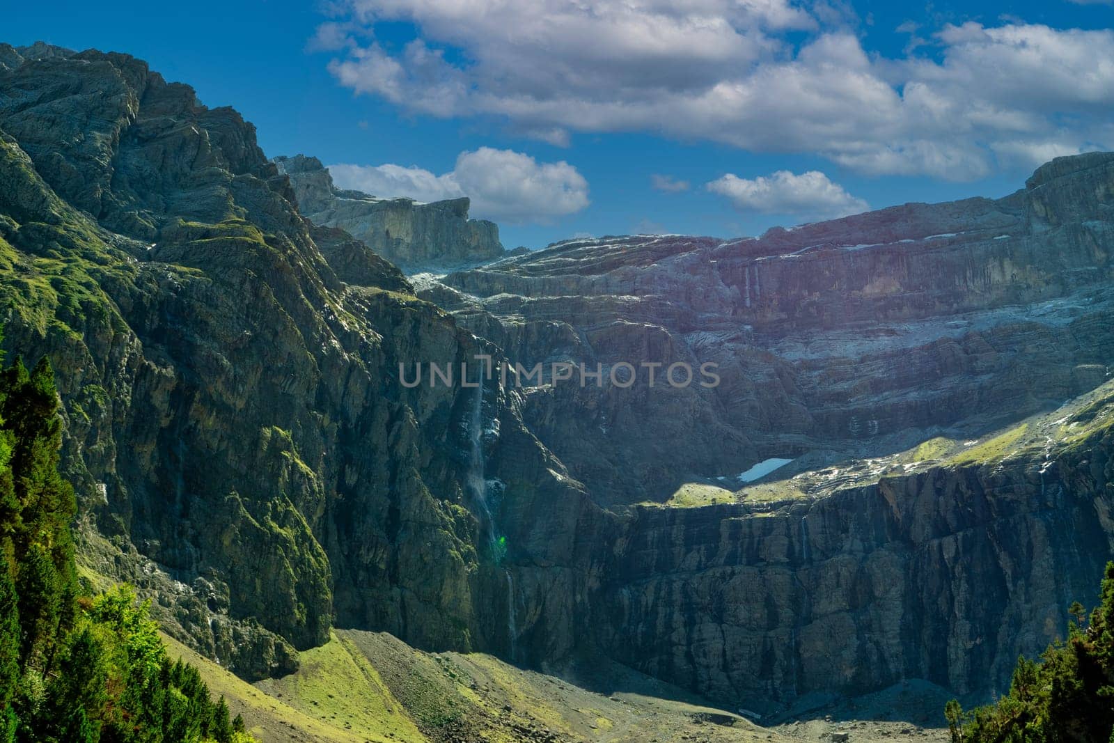 the mountain with a waterfall in the foreground. The waterfall is small and the mountain is very tall, Cirque de Gavarnie, France