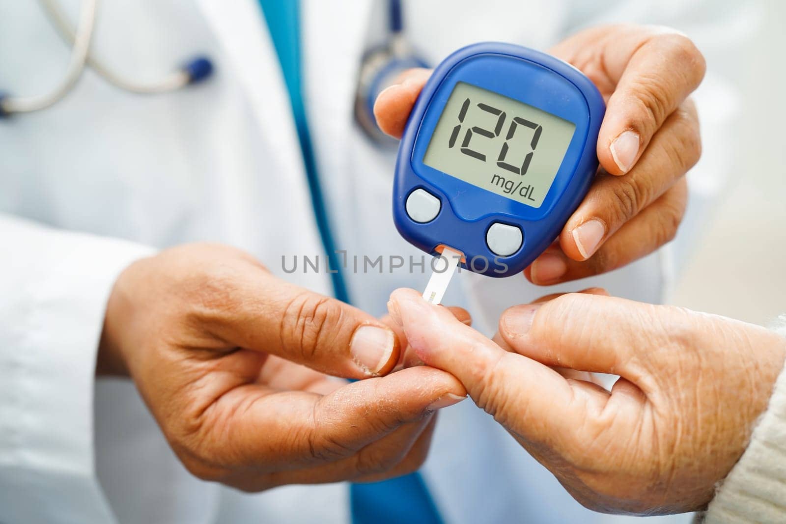 Asian doctor using digital glucose meter for check sample blood sugar level to treatment diabetes.