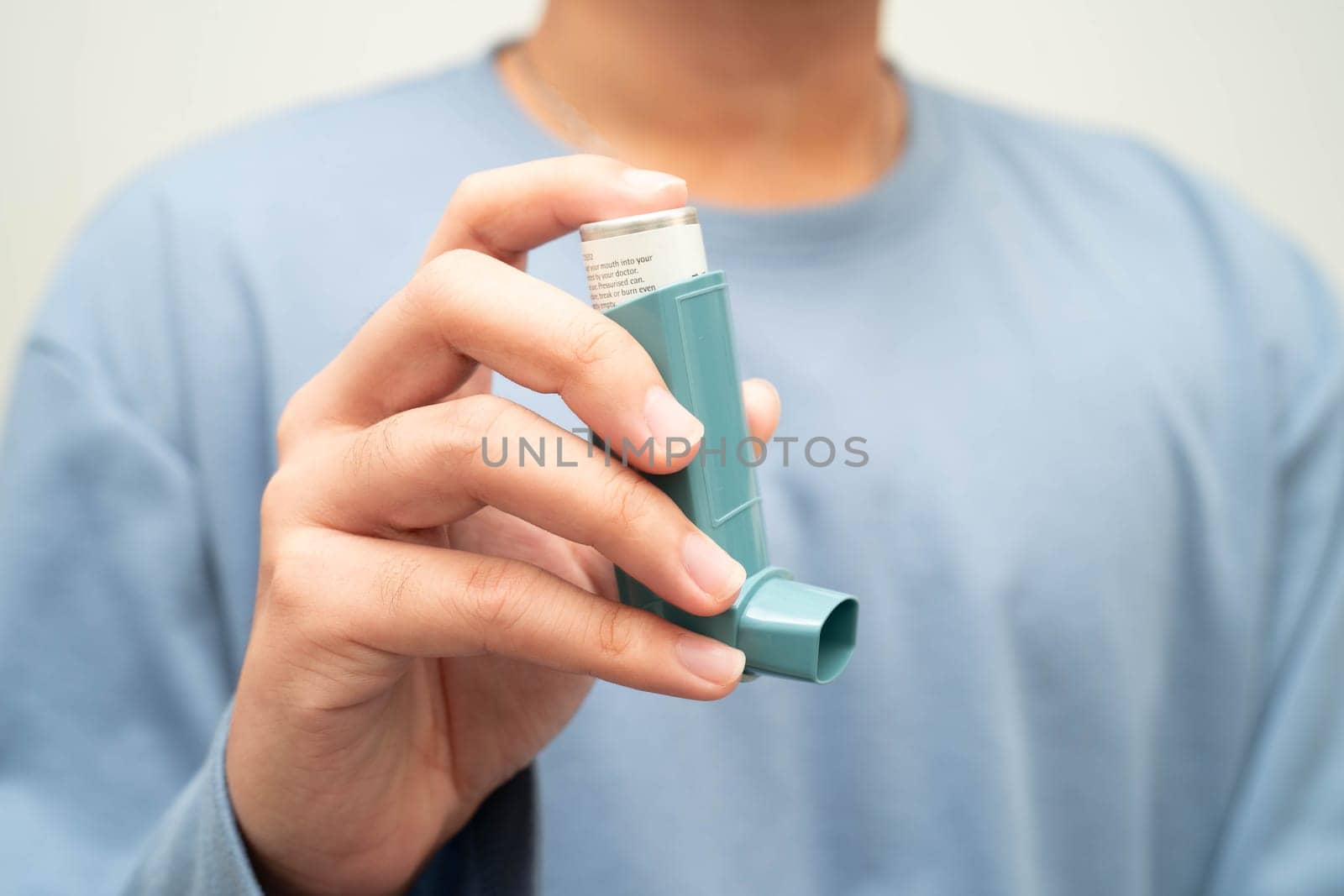 Asthma and chronic obstructive pulmonary disease COPD, Asian young man using metered dose inhaler MDI.