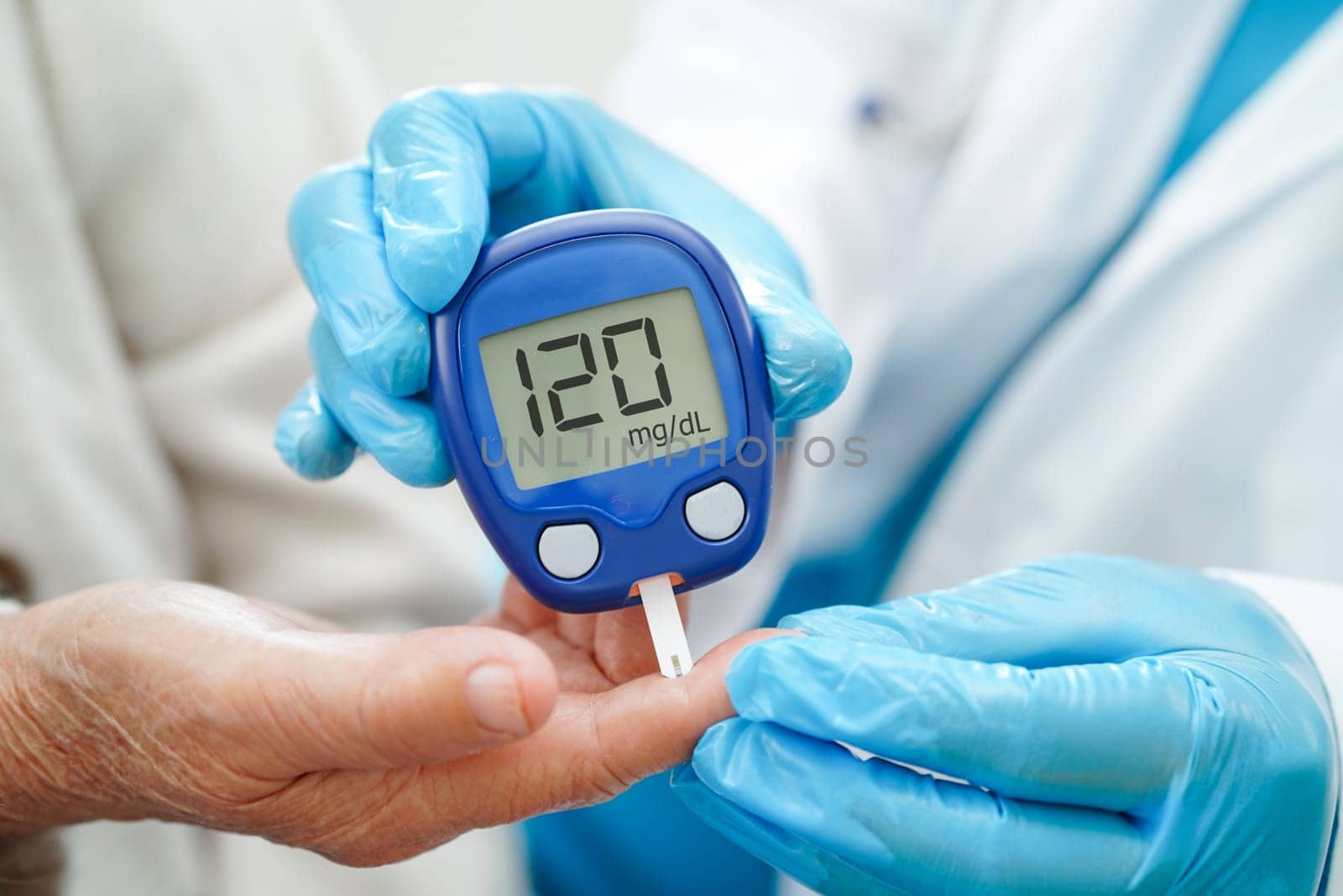 Asian doctor using digital glucose meter for check sample blood sugar level to treatment diabetes.