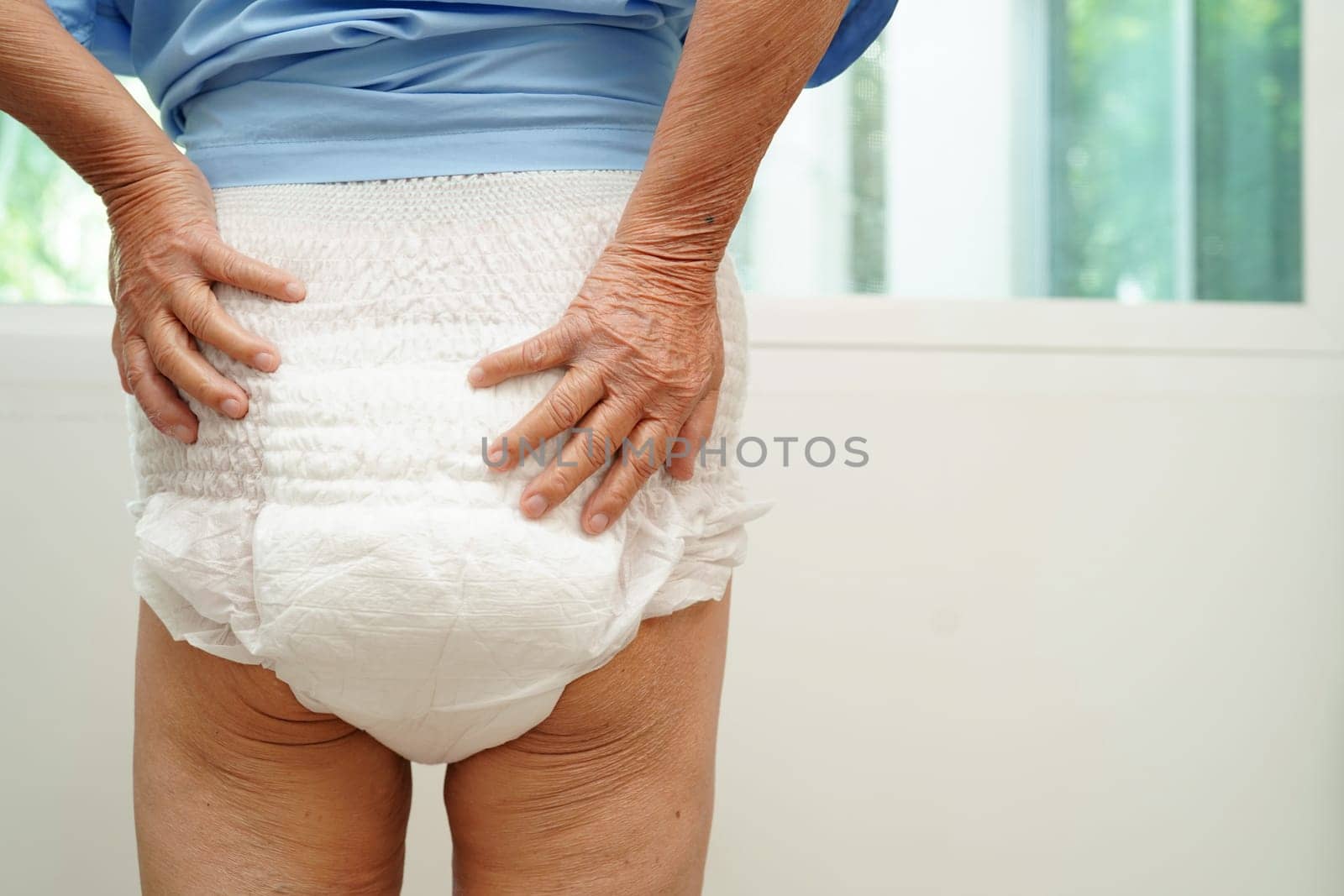 Asian senior woman patient wearing adult incontinence diaper pad in hospital.