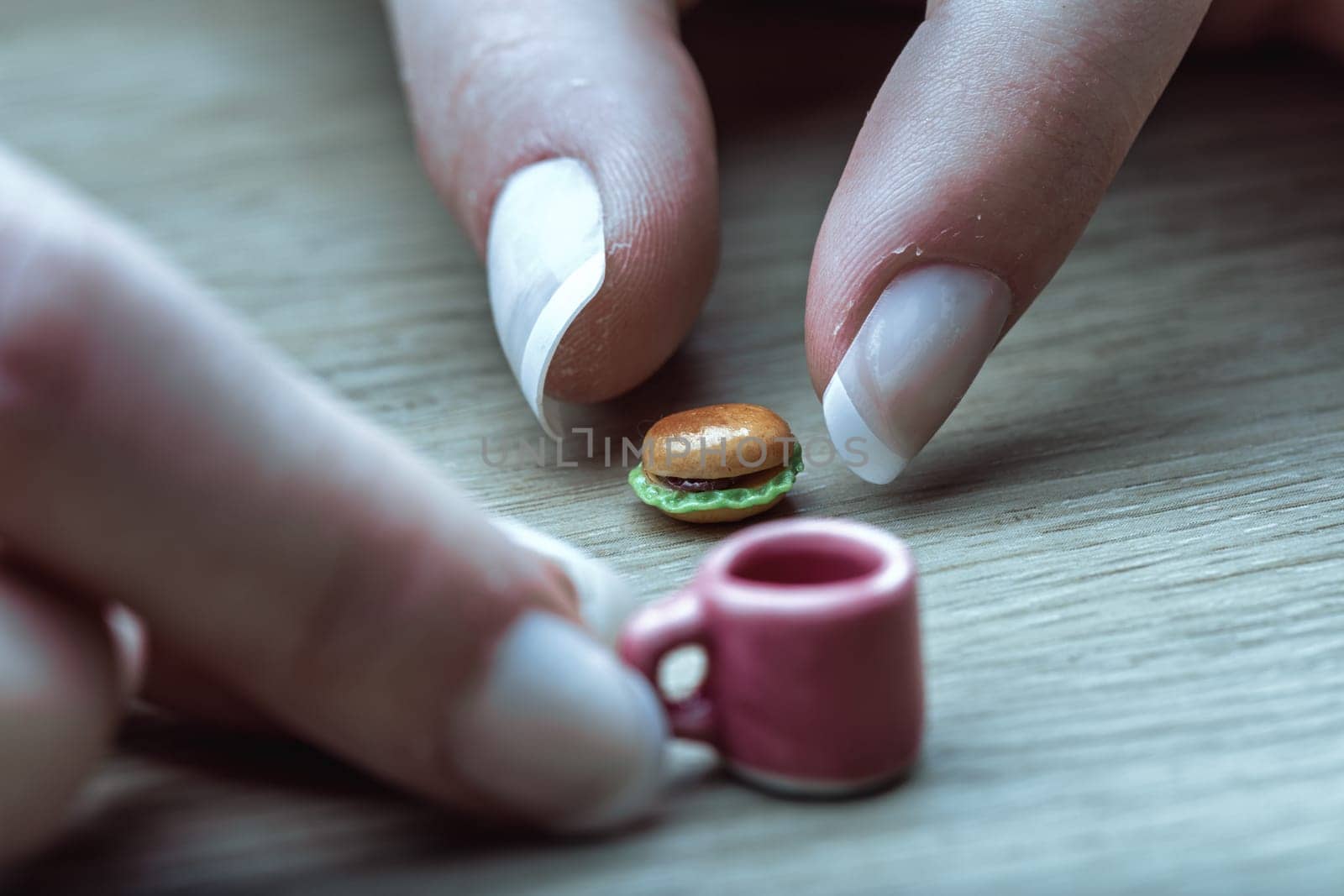 Tiny burger and coffee illustrate correct nutritional portions. Though visually appealing, their minuscule size highlights the challenge of adapting to portion control as advised by dietitians