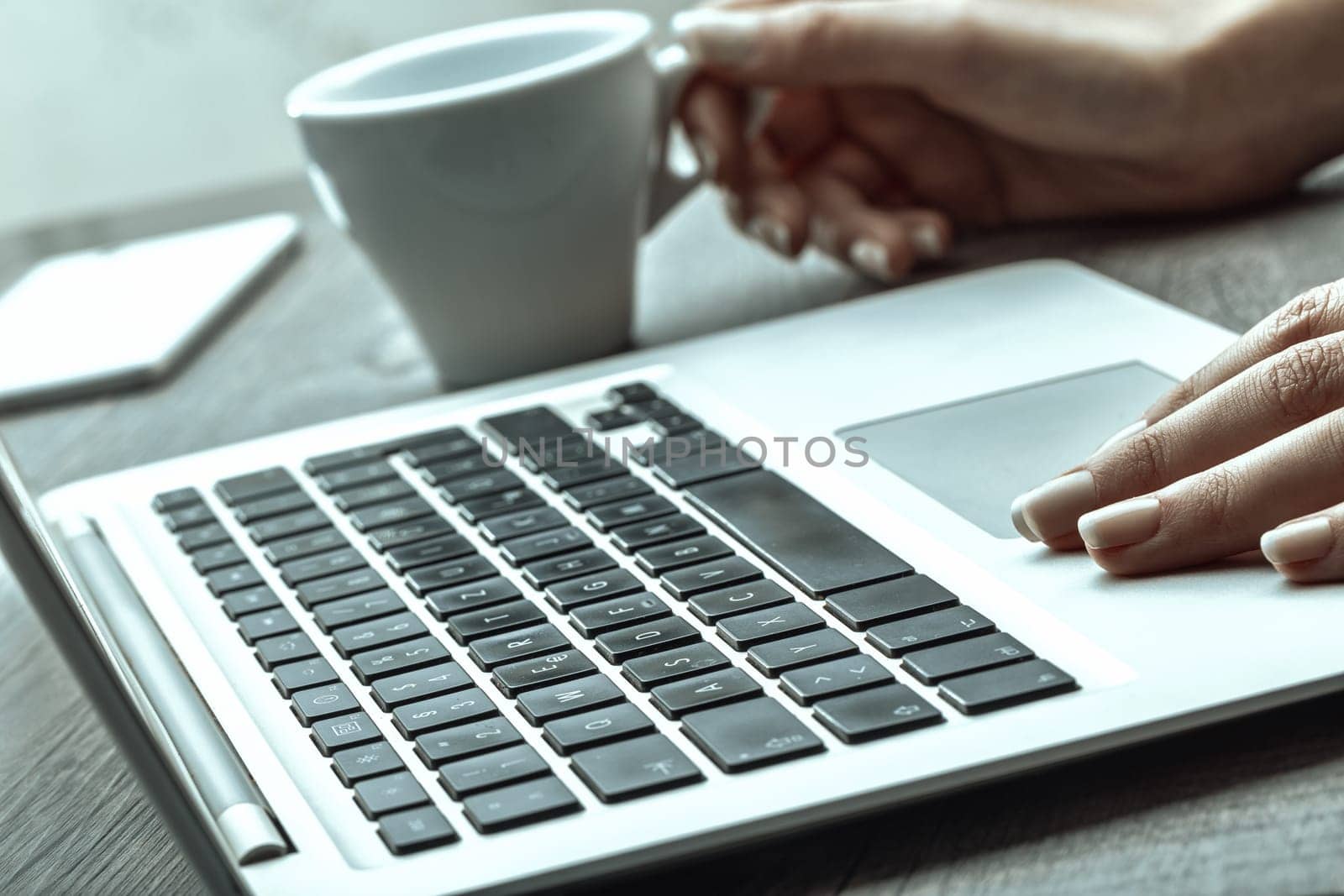 Image features a hand with polished nails on a laptop keyboard, with a coffee cup in the blurred background, evoking a serene, productive workspace vibe