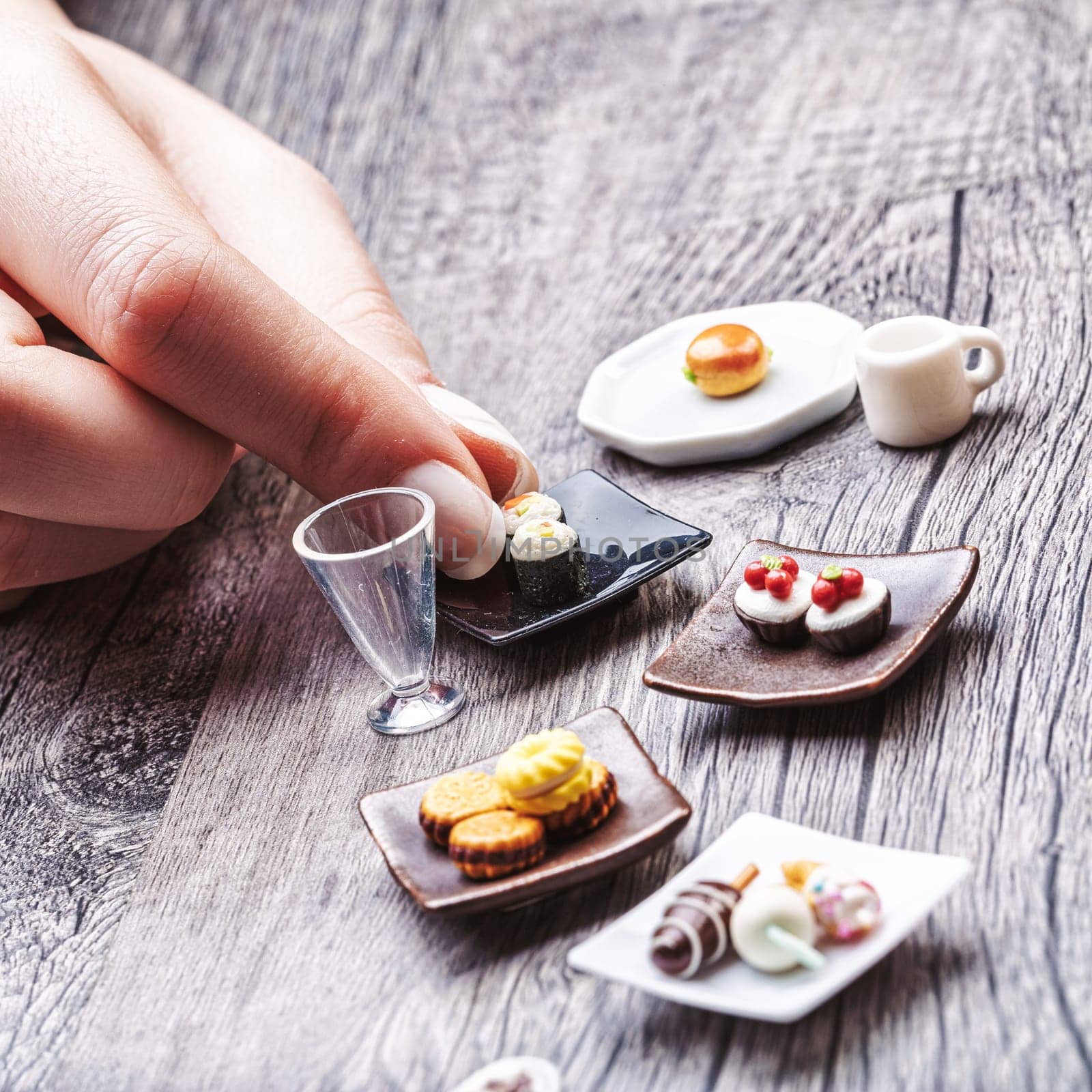 Delicate miniature foods, from sushi to cappuccinos, reflect the difficulty of adhering to nutritional portions. While beautiful, they seem insufficient for true satisfaction