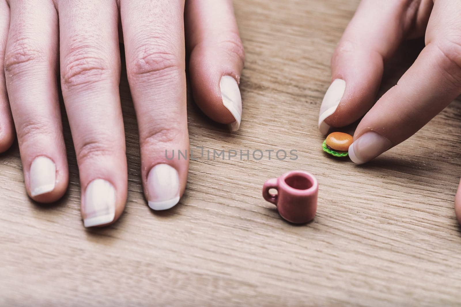 Miniature burger and coffee cup showcase the difficulty of portion control. Although correct, their size visually represents the struggle of adjusting to recommended dietary portions.