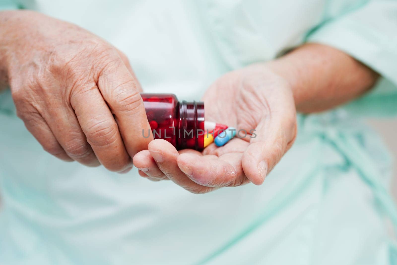 Asian elderly woman holding pill drug in hand, strong healthy medical concept.