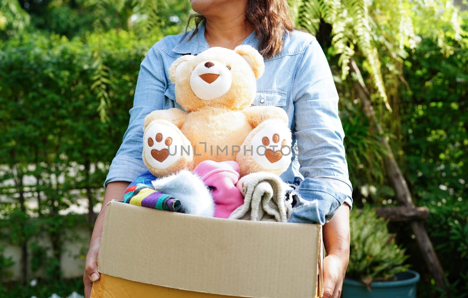 Volunteer collect cloth and doll in cardboard box to donate.