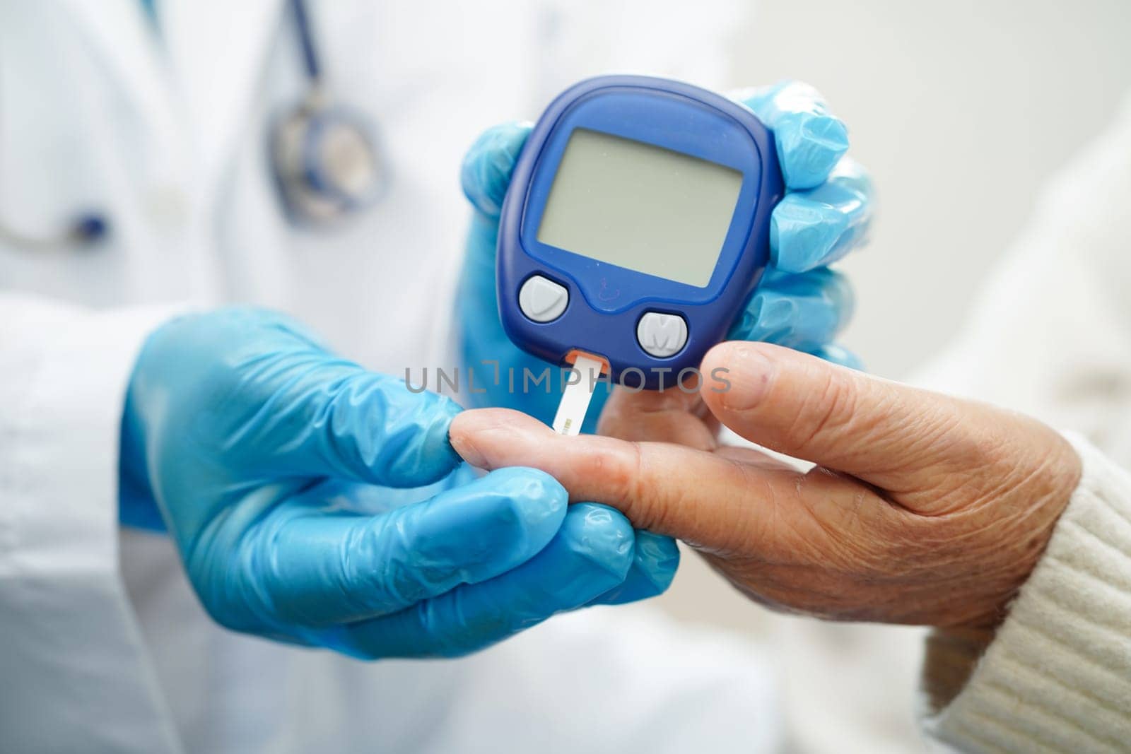 Asian doctor using digital glucose meter for check sample blood sugar level to treatment diabetes.