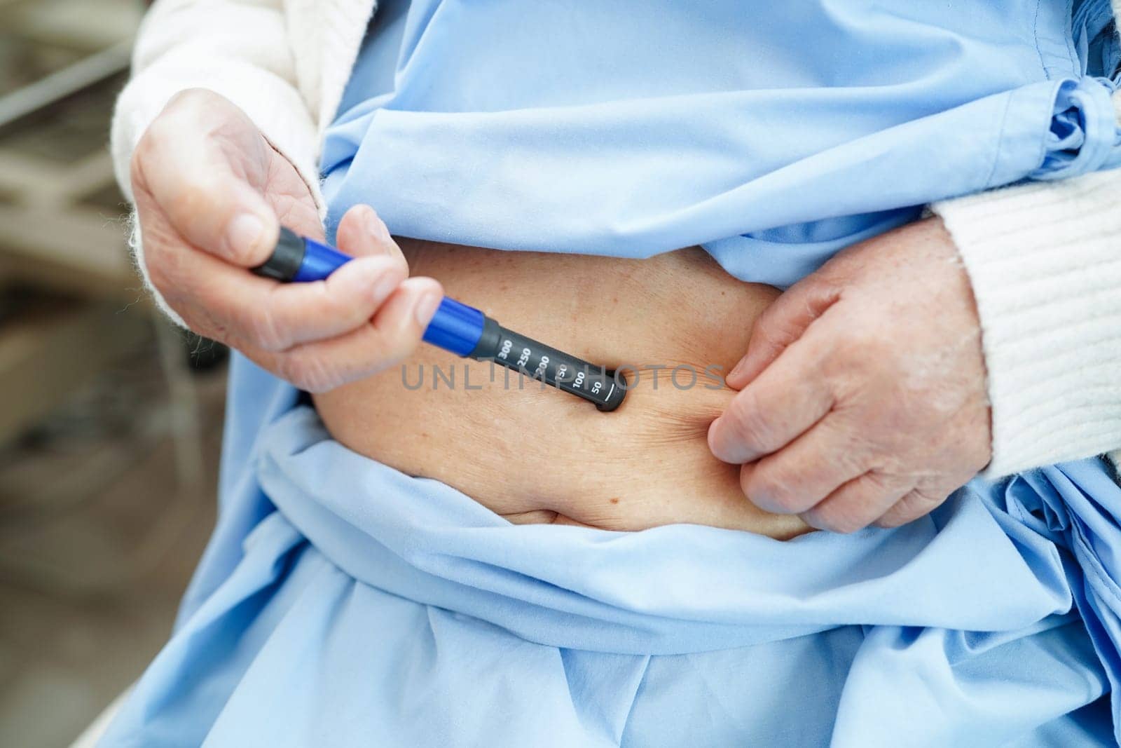 Asian senior woman making injection insulin pen in belly to treatment diabetes.