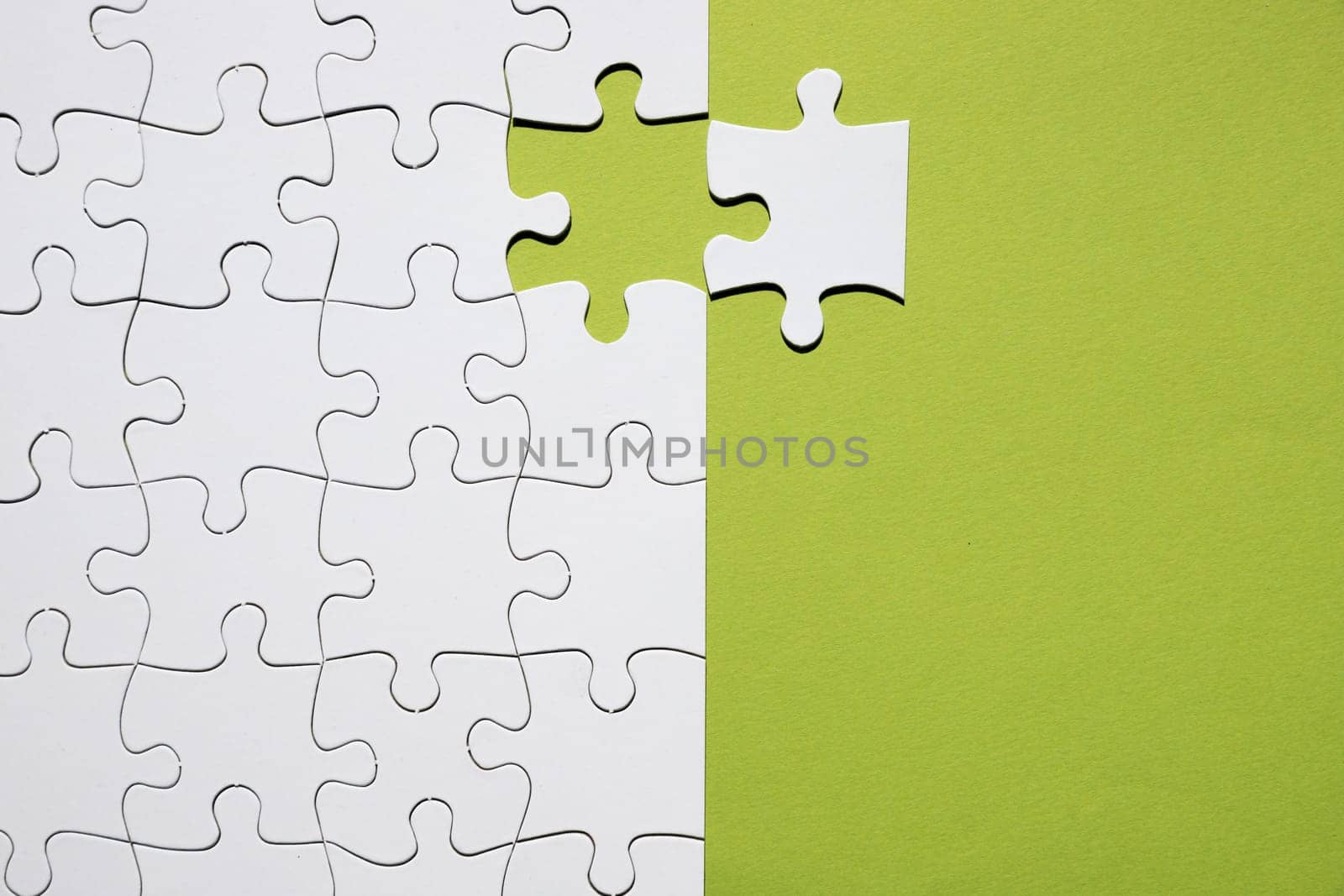 white puzzle piece separate with white puzzle grid green backdrop. Resolution and high quality beautiful photo