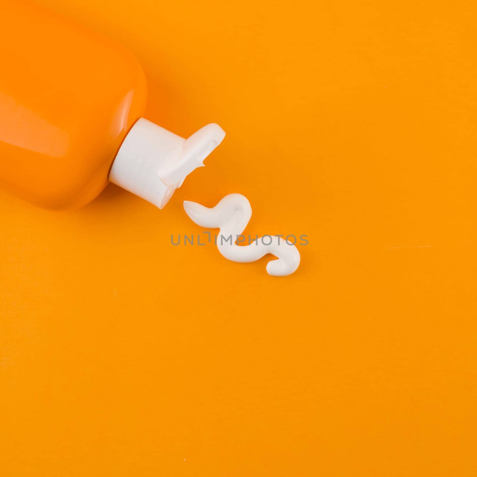 white sunscreen cream coming out orange bottle against orange backdrop. Resolution and high quality beautiful photo