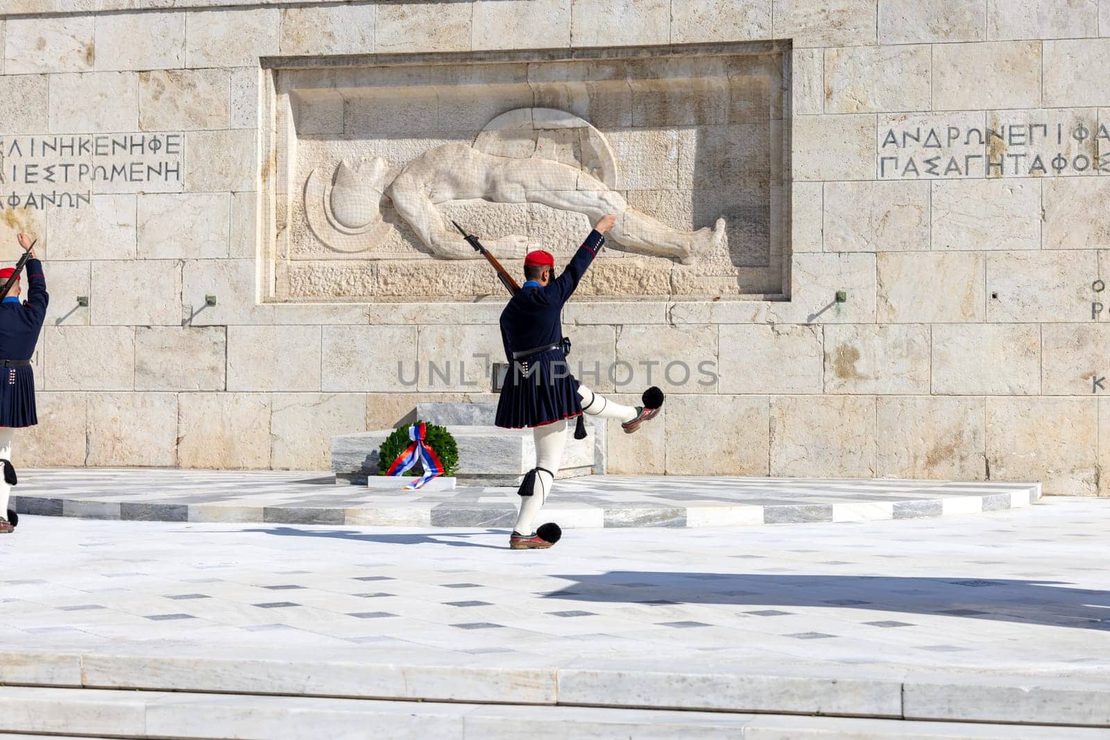 Athens, Greece - October 19, 2022: Changing of the Guard in front of Greek Parliament (Old Royal Palace) by Evzones, Greek representative military formation. On a background Tomb of Unknown Soldier.
