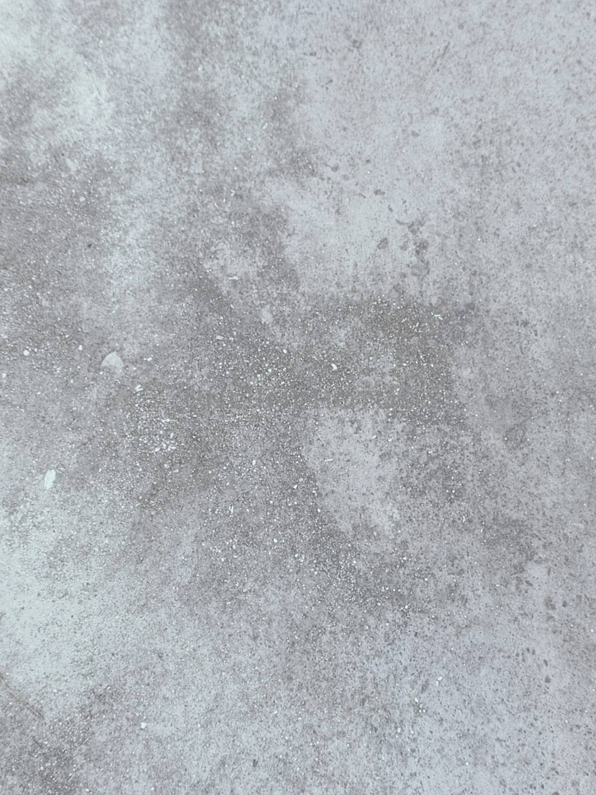 A grey and white wall with a few spots of color. The wall is made of concrete and has a rough texture