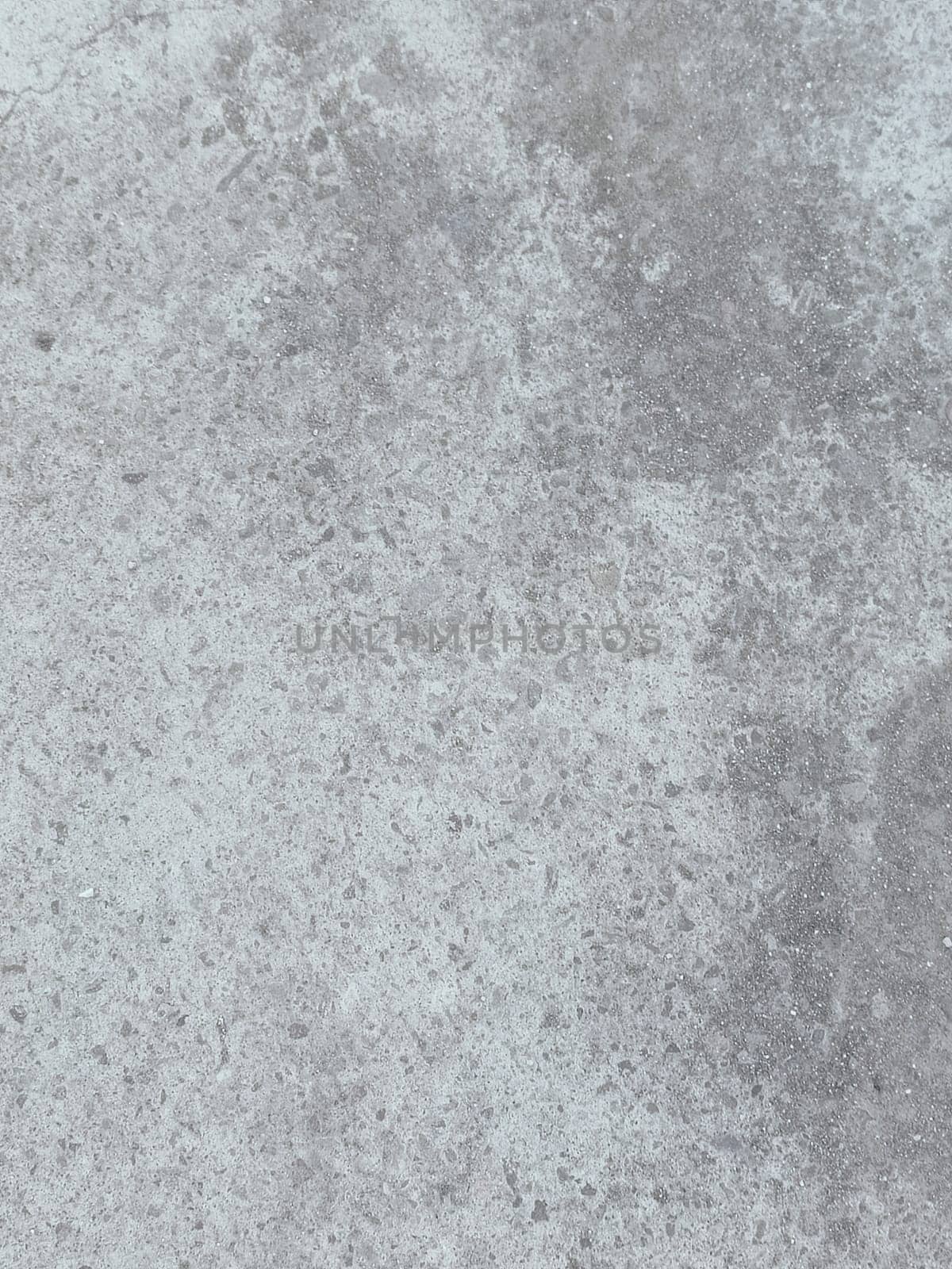 A grey and white wall with a few spots of color. The wall is made of concrete and has a rough texture