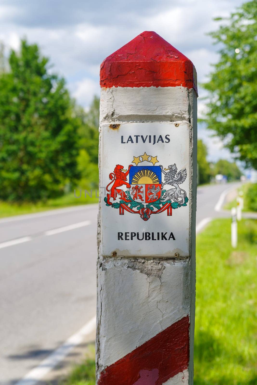 red and white border stone between Latvia and Lithuania with the Latvian coat of arms on it