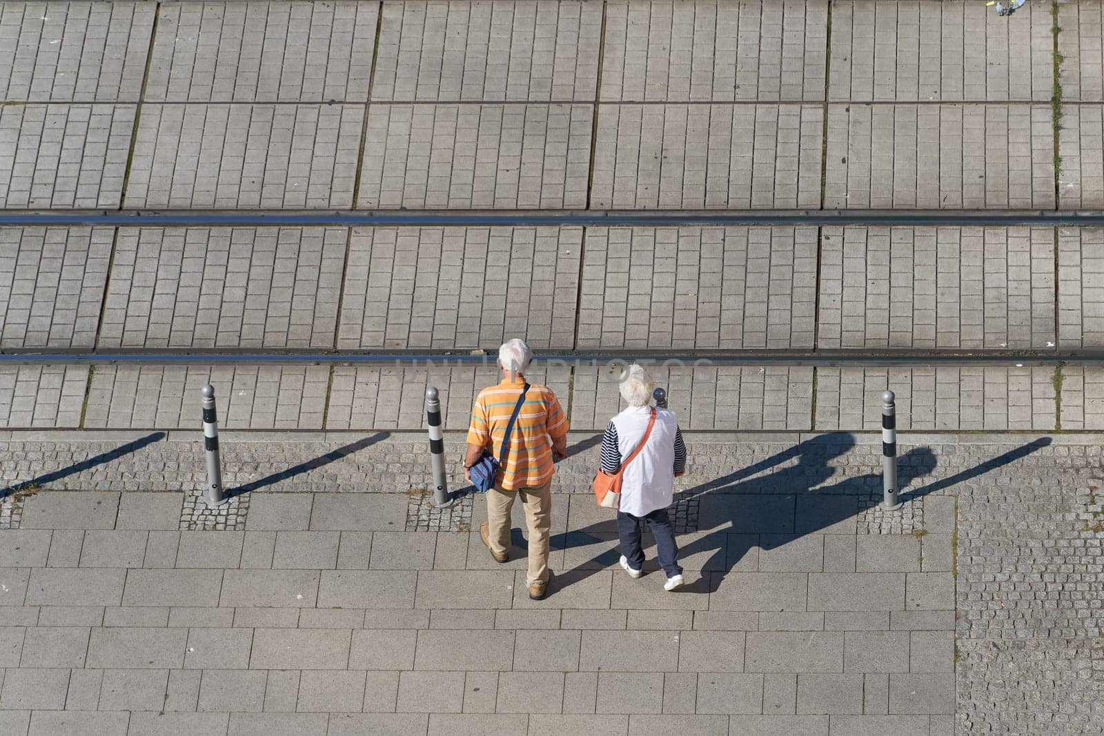 old pensioner couple crossing the tracks of a streetcar in the city center of Magdeburg in Germany