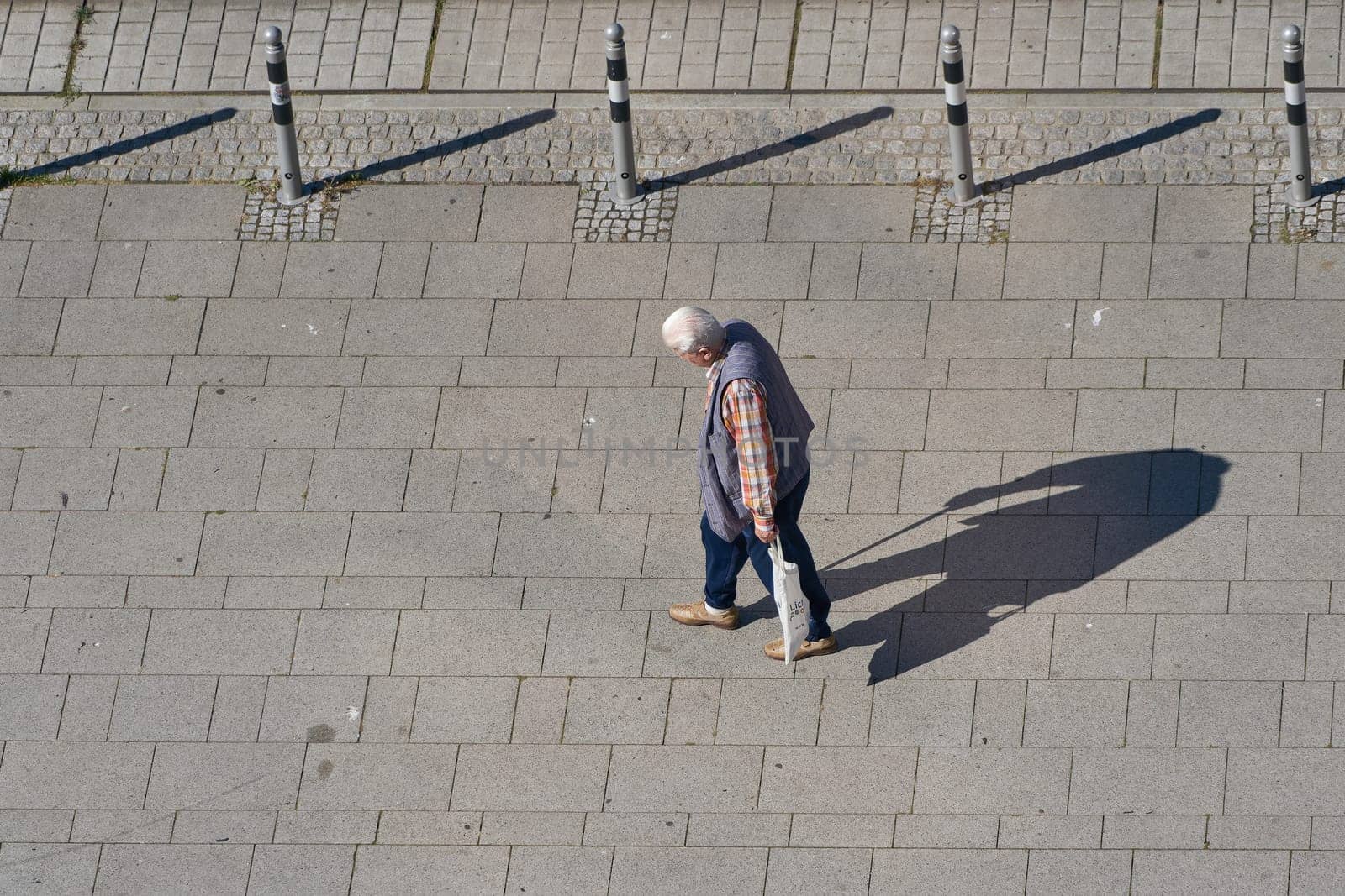old pensioner on a footpath in a pedestrian zone with text space on the left side