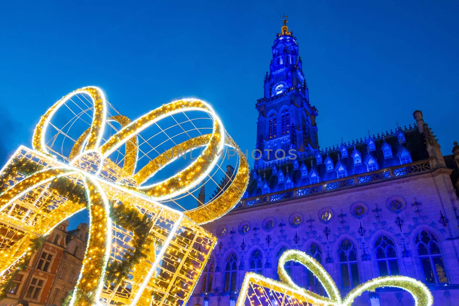 Arras, France - December 30, 2023: View of the Belfry and Christmas decorations on the illuminated square, photograph taken during the holiday season