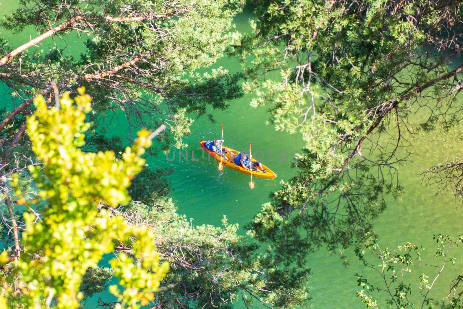 Canyon of the Tarn river, Occitanie, France - June 30 2016: Orange canoe-kayak through the trees in the gorges du Tarn