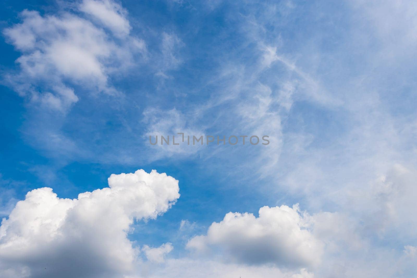 Fluffy white clouds on clear blue sky background