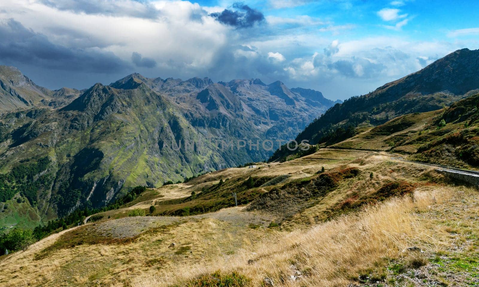 a mountains are covered in lush green trees and the sky is overcast. The landscape is peaceful and serene. Pyrenees, France