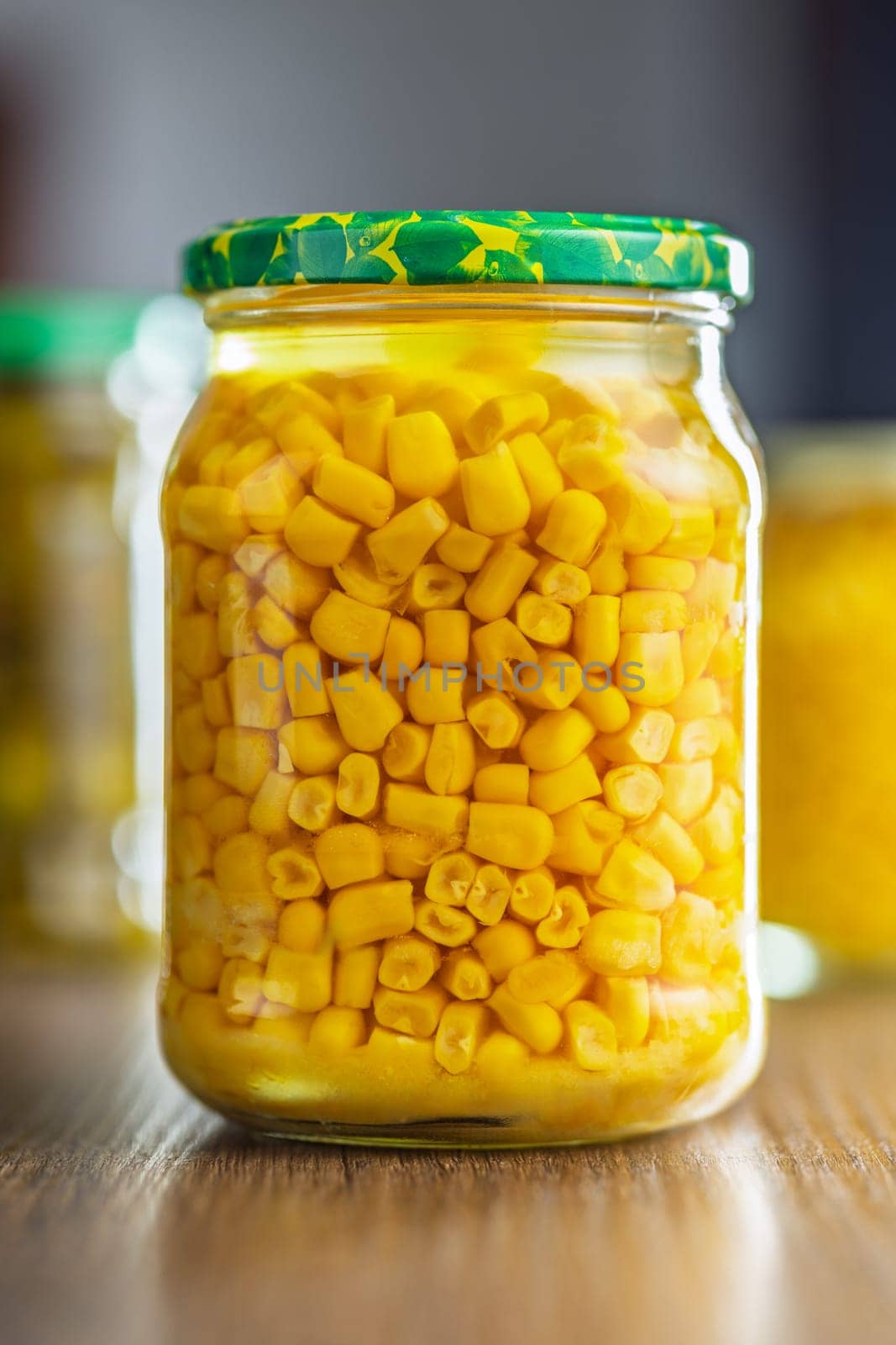 Canned sweet corn in jar on a wooden table.