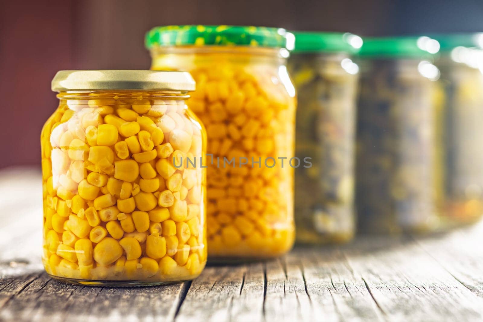 Canned sweet corn in jar on a wooden table.