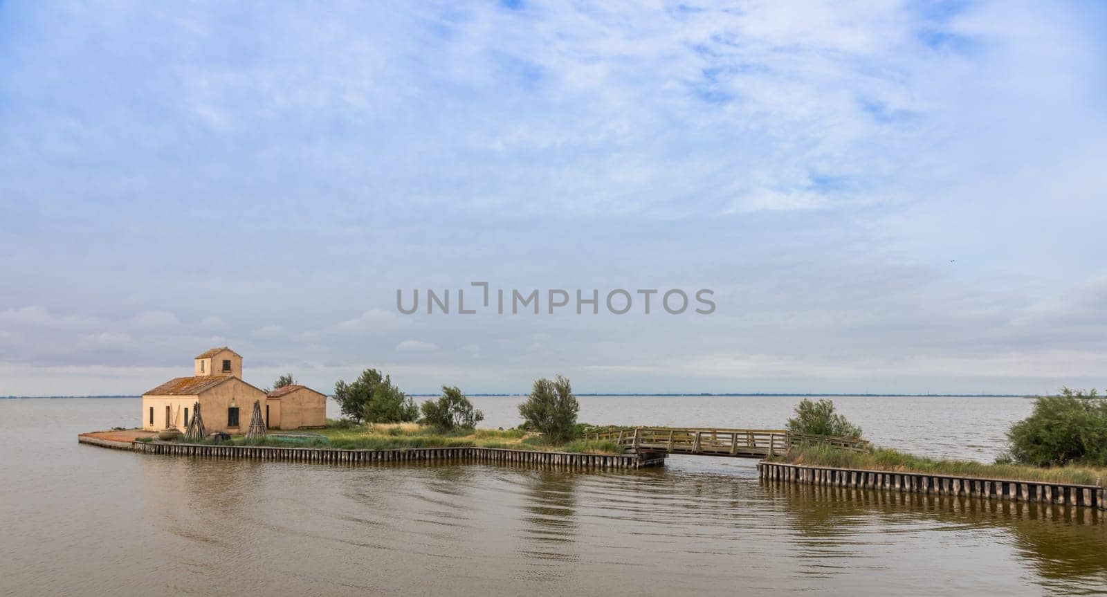 Comacchio, Italy - 13 June 2024. Casone Donnabona, traditional house for fishermen in lagoon. Wetland, blue sky.