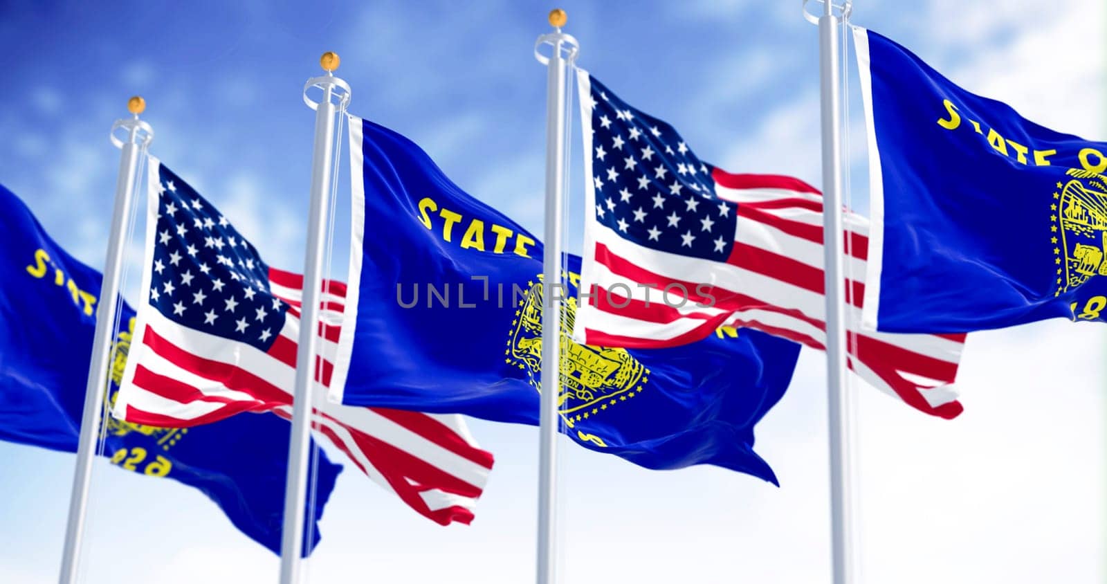 Oregon state flags waving in the wind with the american flags on a clear day. The Oregon flag is two-sided with navy blue and gold colors. Selective focus. Fluttering fabric. Waving flag
