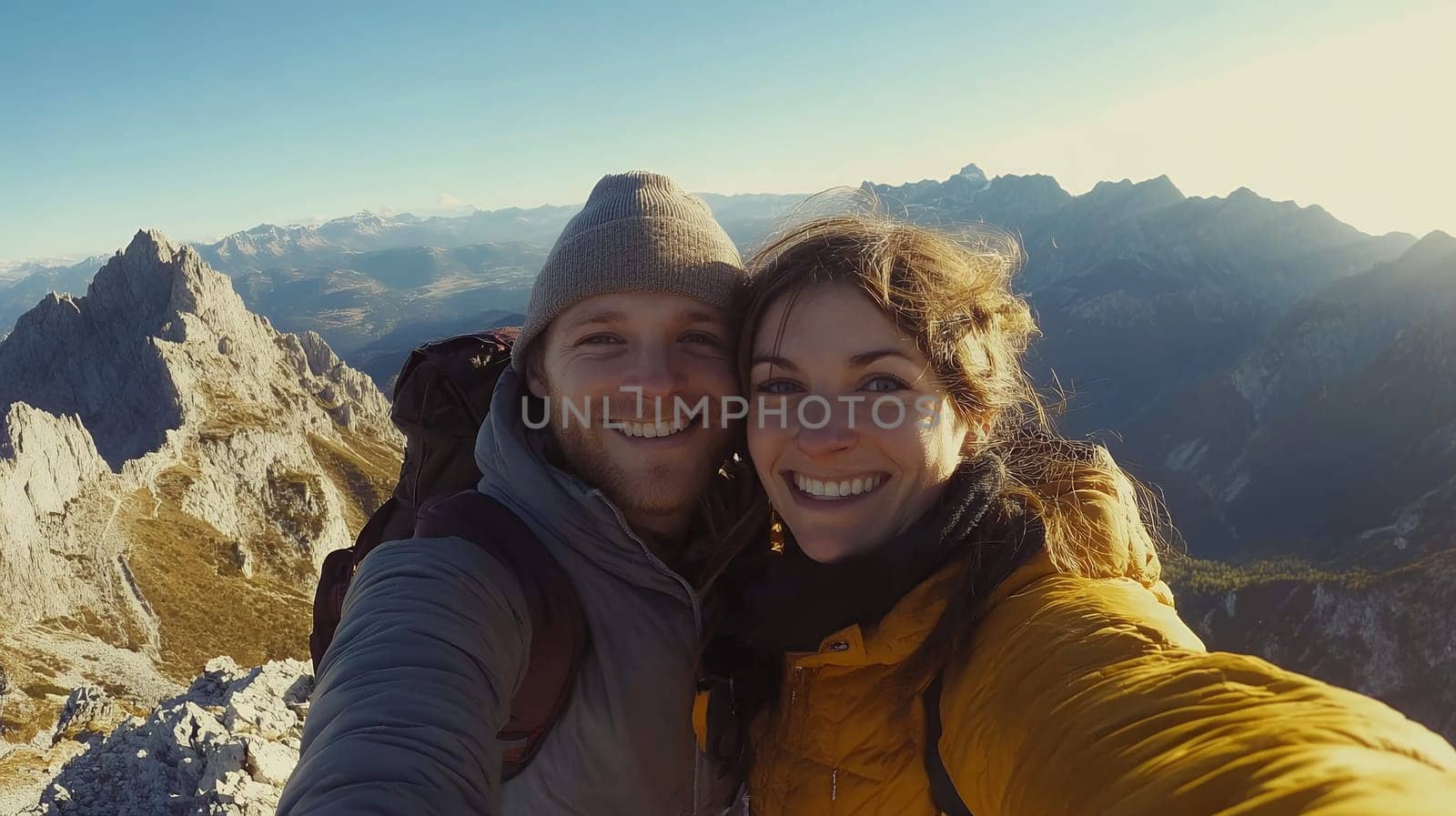 A smiling couple takes a selfie on a mountain peak, capturing their adventurous spirit and love of nature.