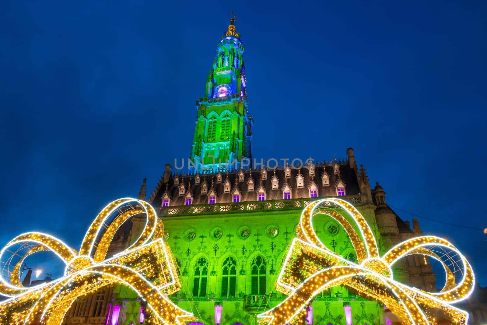 Arras, France - December 30, 2023: View of the Belfry and Christmas decorations on the illuminated square, photograph taken during the holiday season