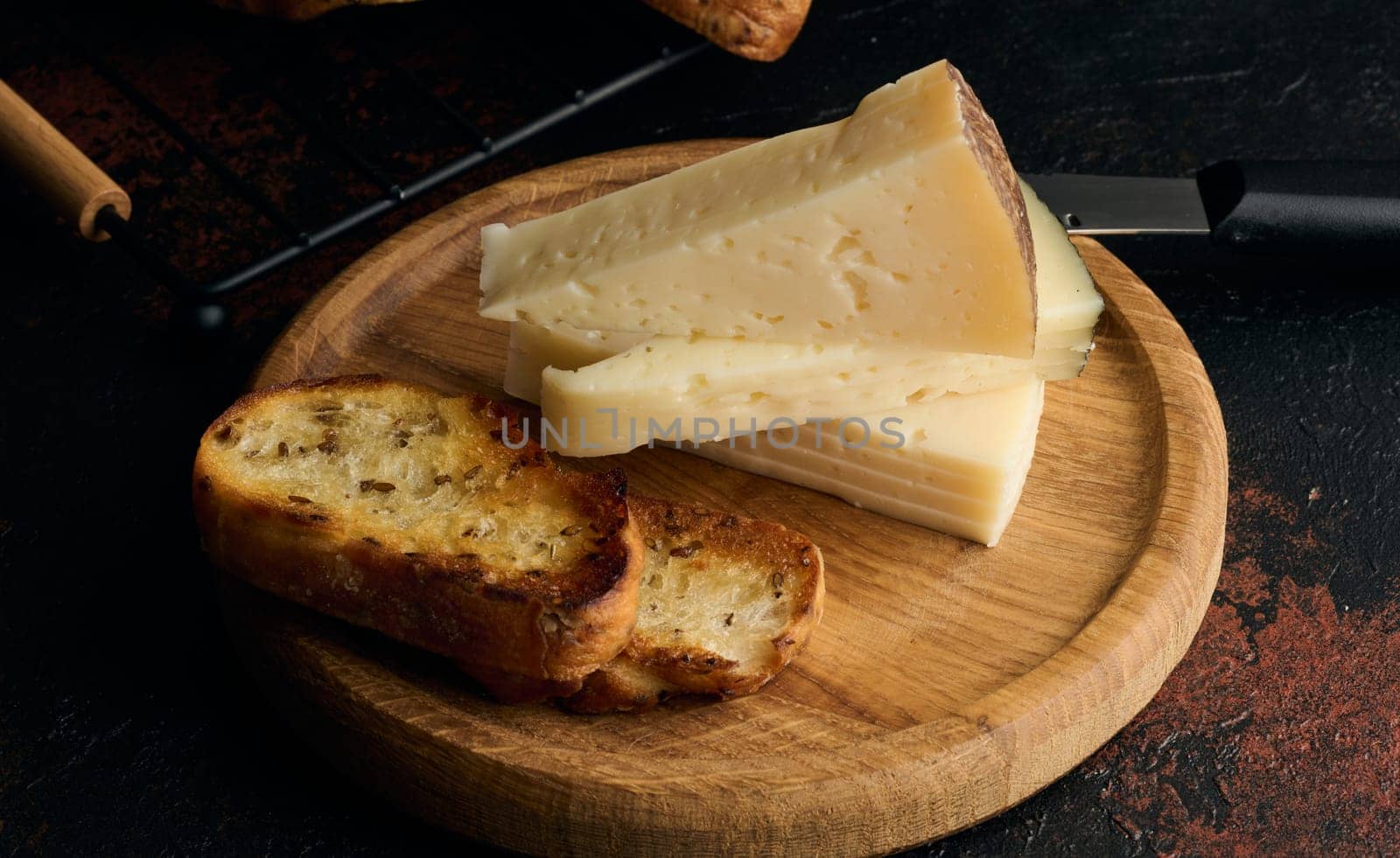 Triangular pieces of cheese and fried ciabatta slices on a wooden board