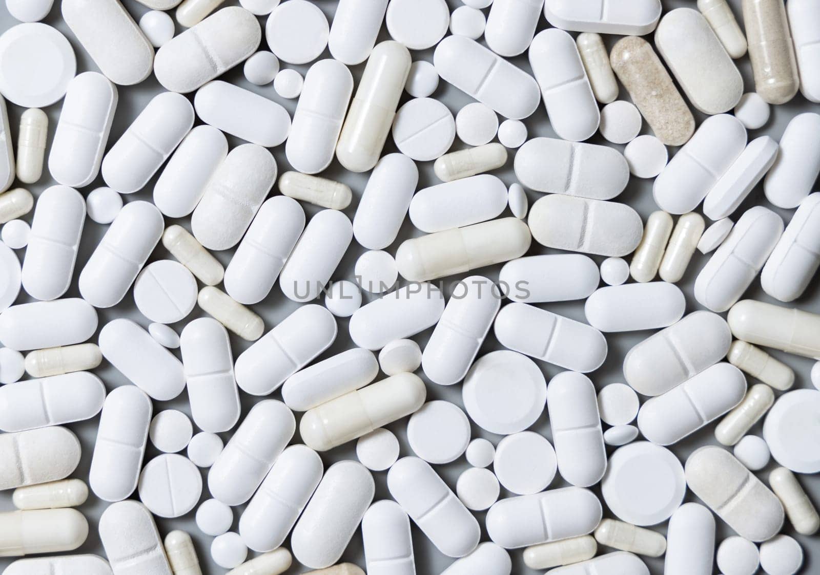 Mix of medical capsules and pills on grey top view. Preventive medicine and healthcare, taking dietary supplements and vitamins. Assorted pharmaceutical medicine capsules