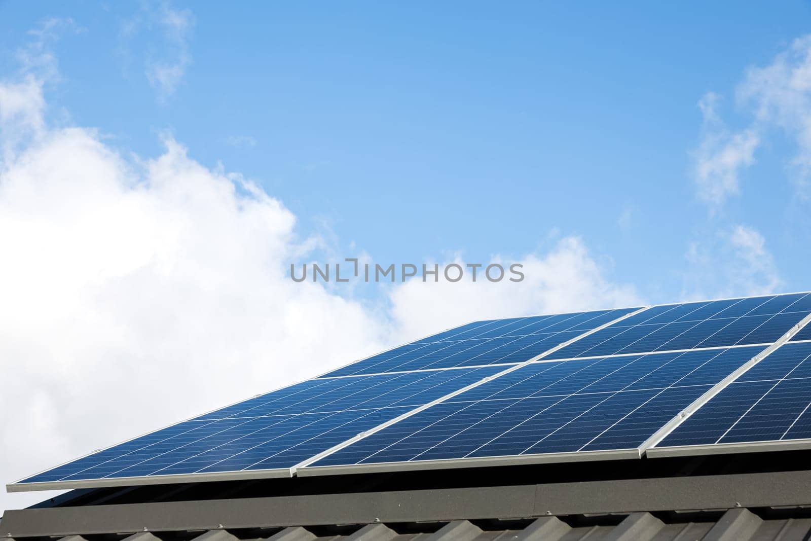 Aerial view of solar panel cells against cloudy blue sky. Alternative energy concept, sustainable resources. House with solar panels stand-alone photovoltaic plant system. Professional installation