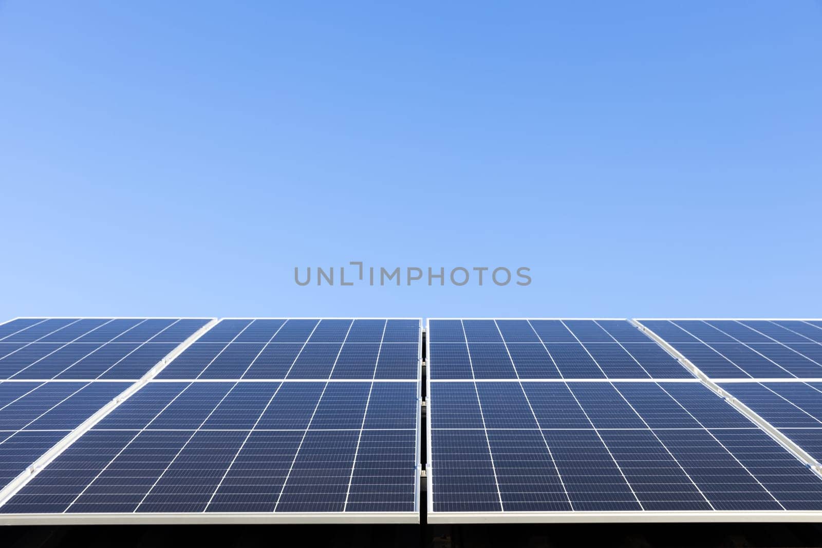 Aerial view of solar panel cells on clear blue sky background. Alternative energy concept. Modern house with solar panels stand-alone photovoltaic plant system on household metal sheet roof