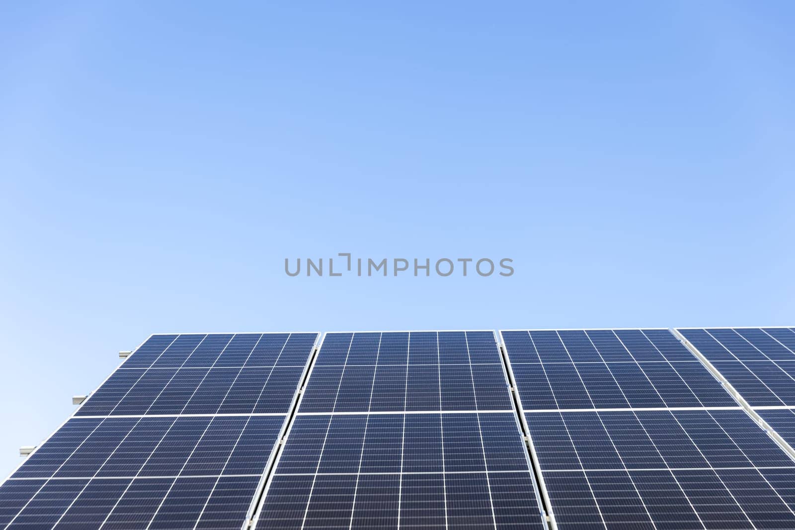 Aerial view of solar panel cells on clear blue sky background. Alternative energy concept. Modern house with solar panels stand-alone photovoltaic plant system on household metal sheet roof