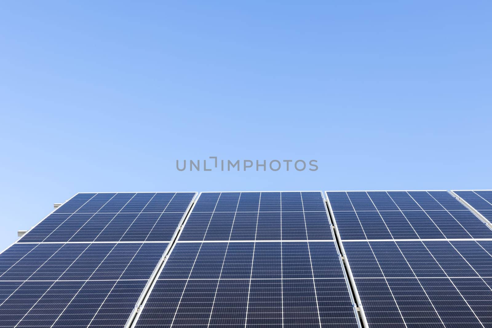 Aerial view of solar panel cells on clear blue sky background. Alternative energy concept. Modern house with solar panels stand-alone photovoltaic plant system on household metal sheet roof