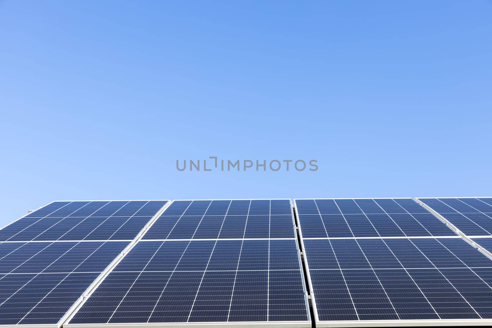Aerial view of solar panel cells on clear blue sky background. Alternative energy concept. Modern house with solar panels stand-alone photovoltaic plant system on household metal sheet roof
