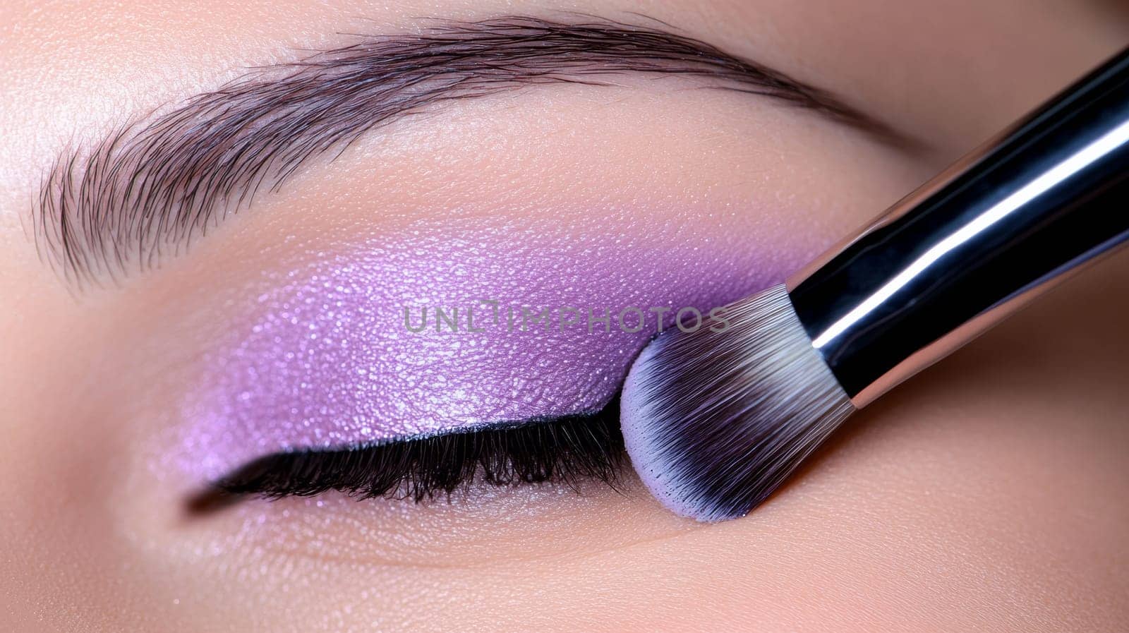 Close-up of an eyeshadow brush applying a rich shade to perfectly shaped eyelids .