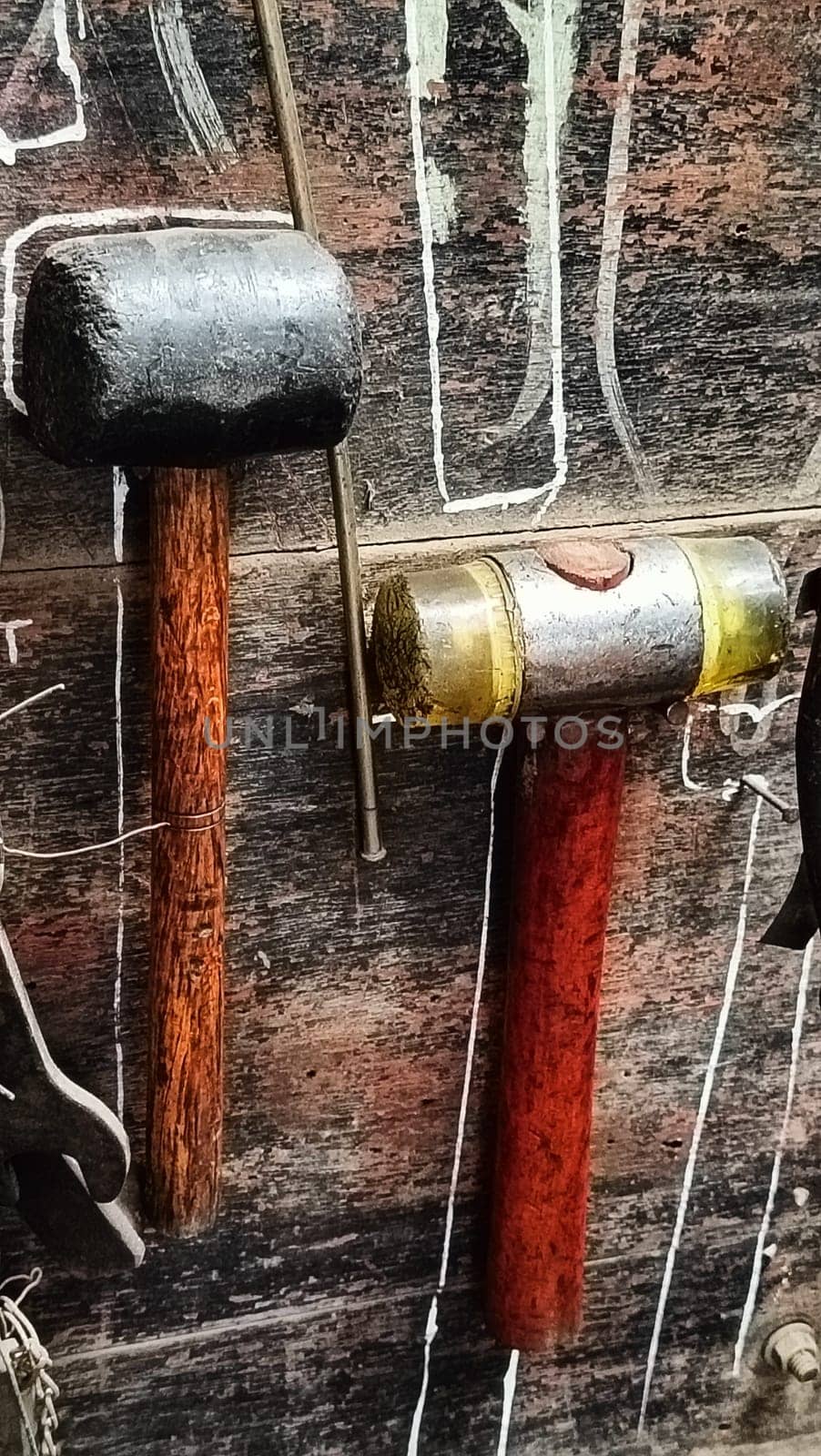 A cluttered workshop scene showcasing an assortment of tools hanging on a wooden wall and surrounding shelves, creating a rustic and industrial atmosphere.
