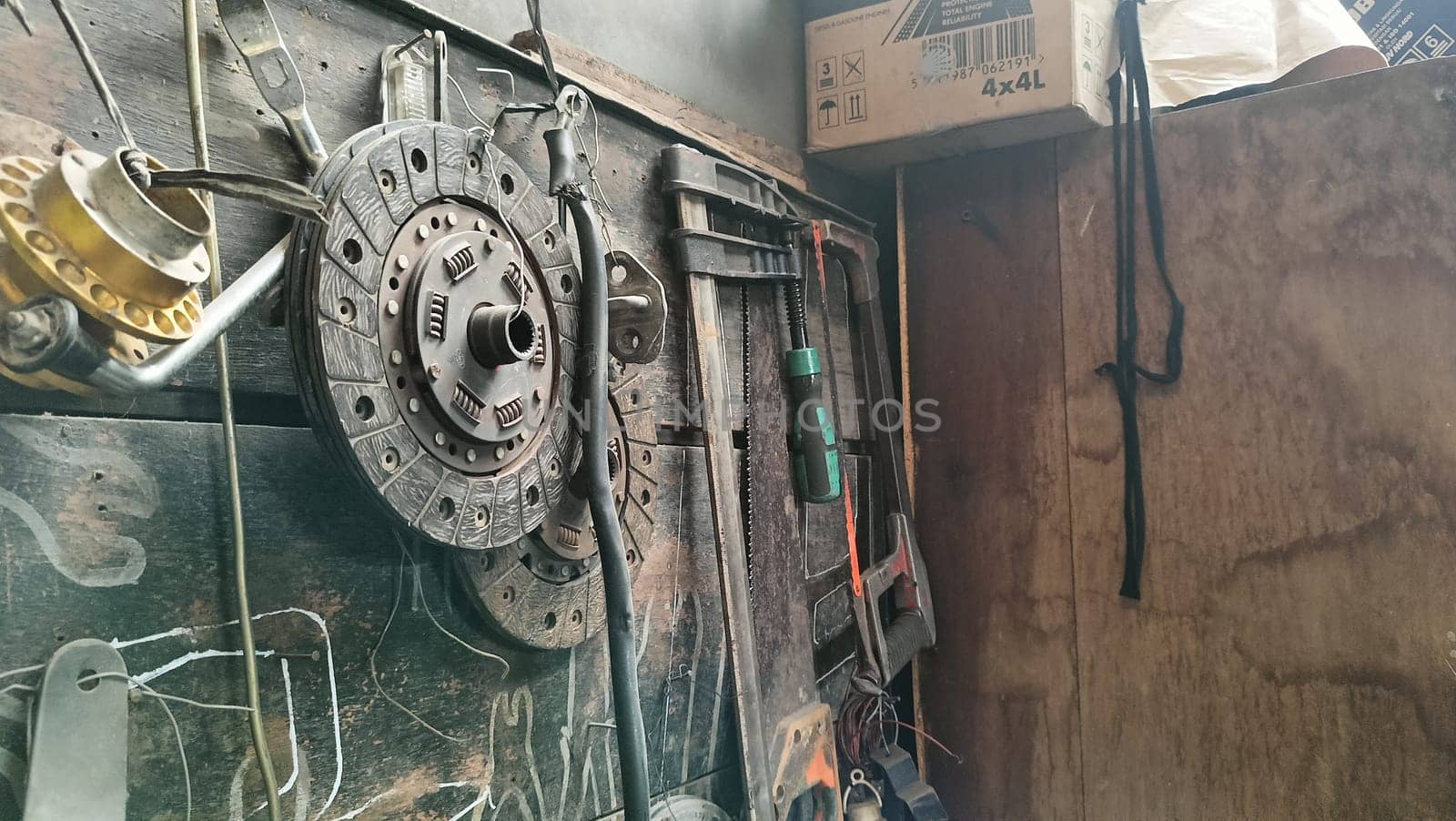 A cluttered workshop scene showcasing an assortment of tools hanging on a wooden wall and surrounding shelves, creating a rustic and industrial atmosphere.