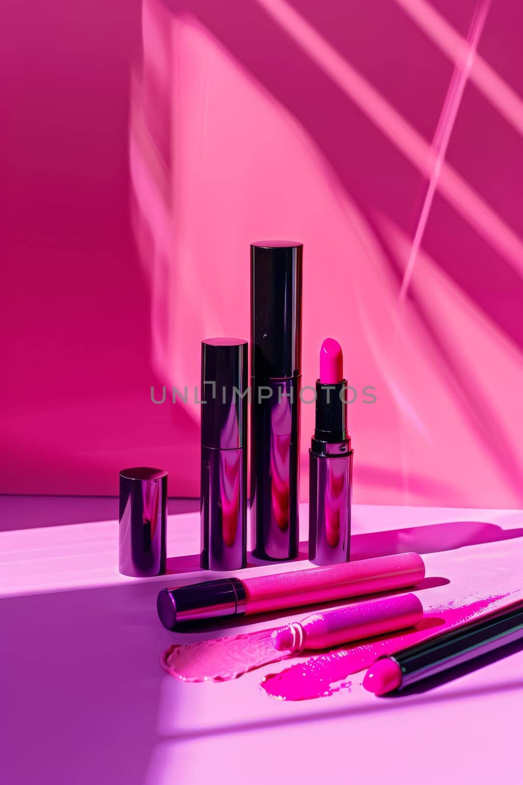 A row of makeup products, including lipsticks and lip glosses, are displayed on a pink background. The products are arranged in a way that highlights their colors and textures