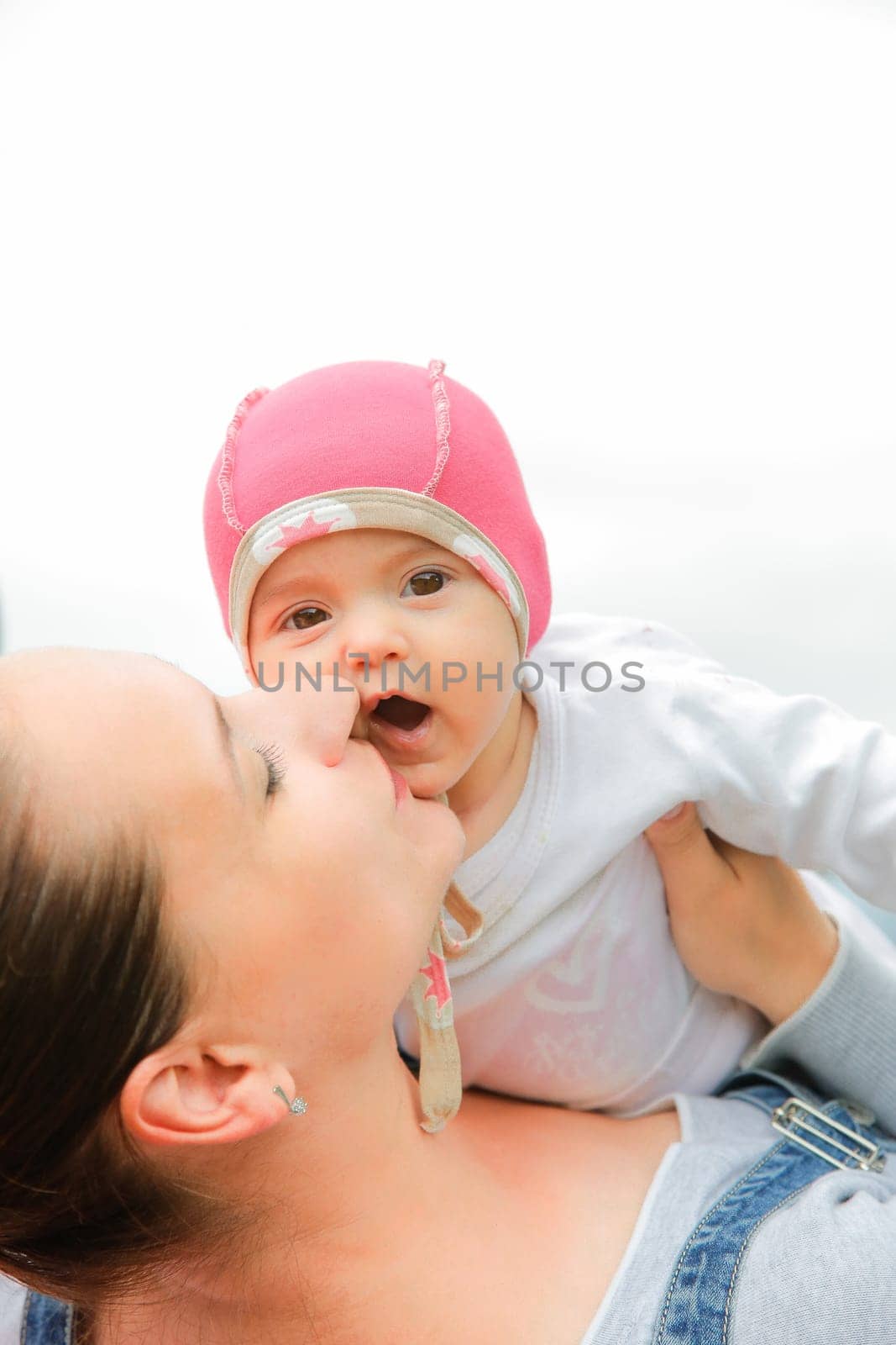 A beautifully heartwarming kiss is lovingly shared between a devoted mother and her joyful, cheerful baby