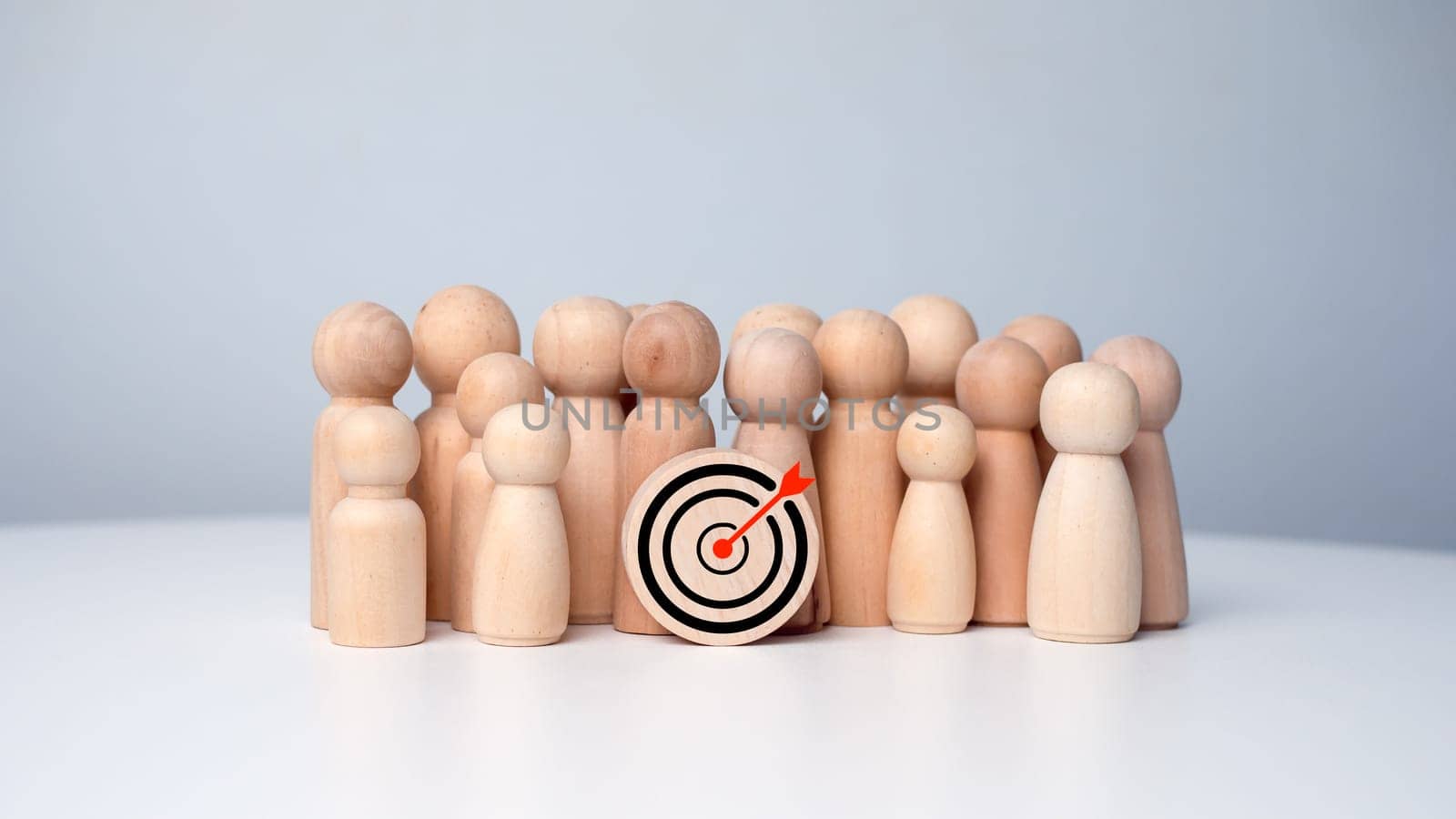 Wooden dolls standing around dart board for creating and targeting business objectives. Target concept of business and personnel in a company. Marketing solutions, targets for business investment.