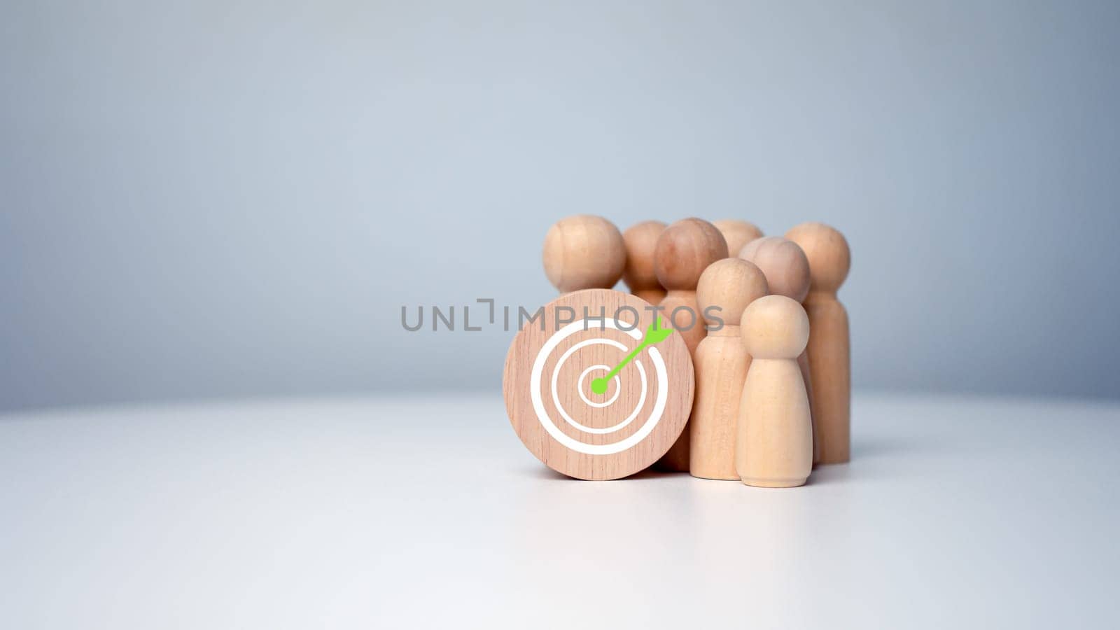 Wooden dolls standing around dart board for creating and targeting business objectives. Target concept of business and personnel in a company. Marketing solutions, targets for business investment.