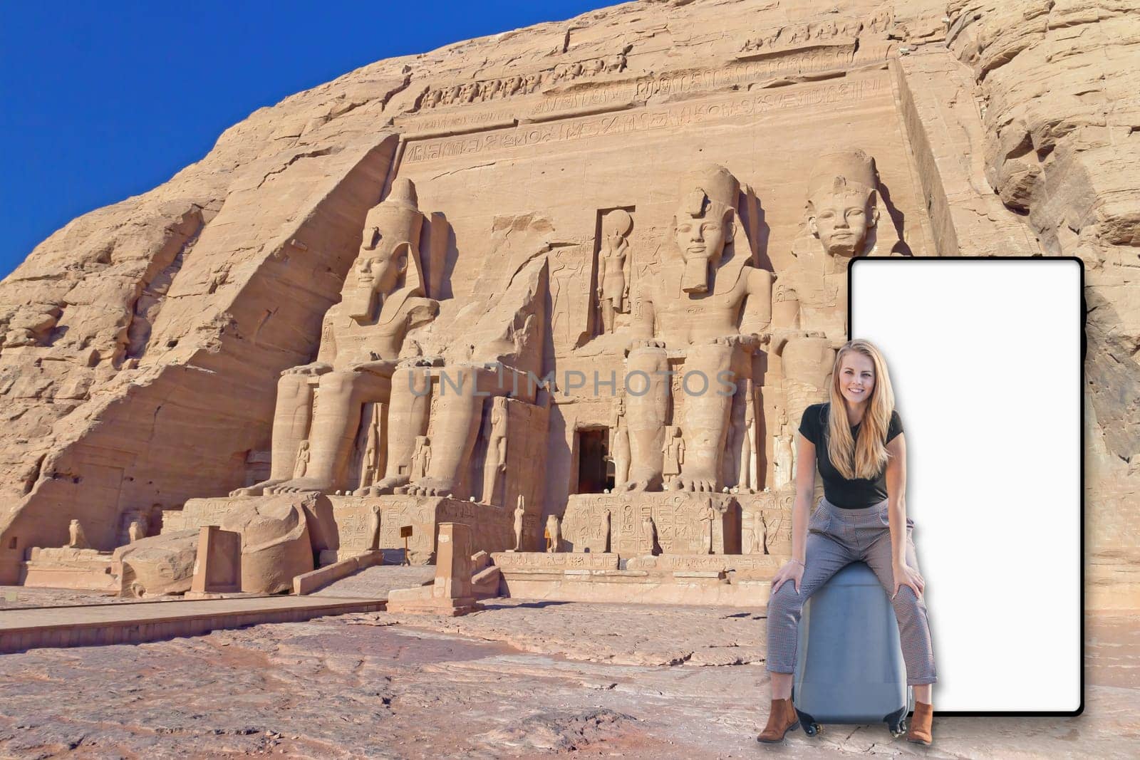 Girl sitting on suitcase in front of Abu Simbel Temple in Egypt. Blank mobile screen is ready for your text.