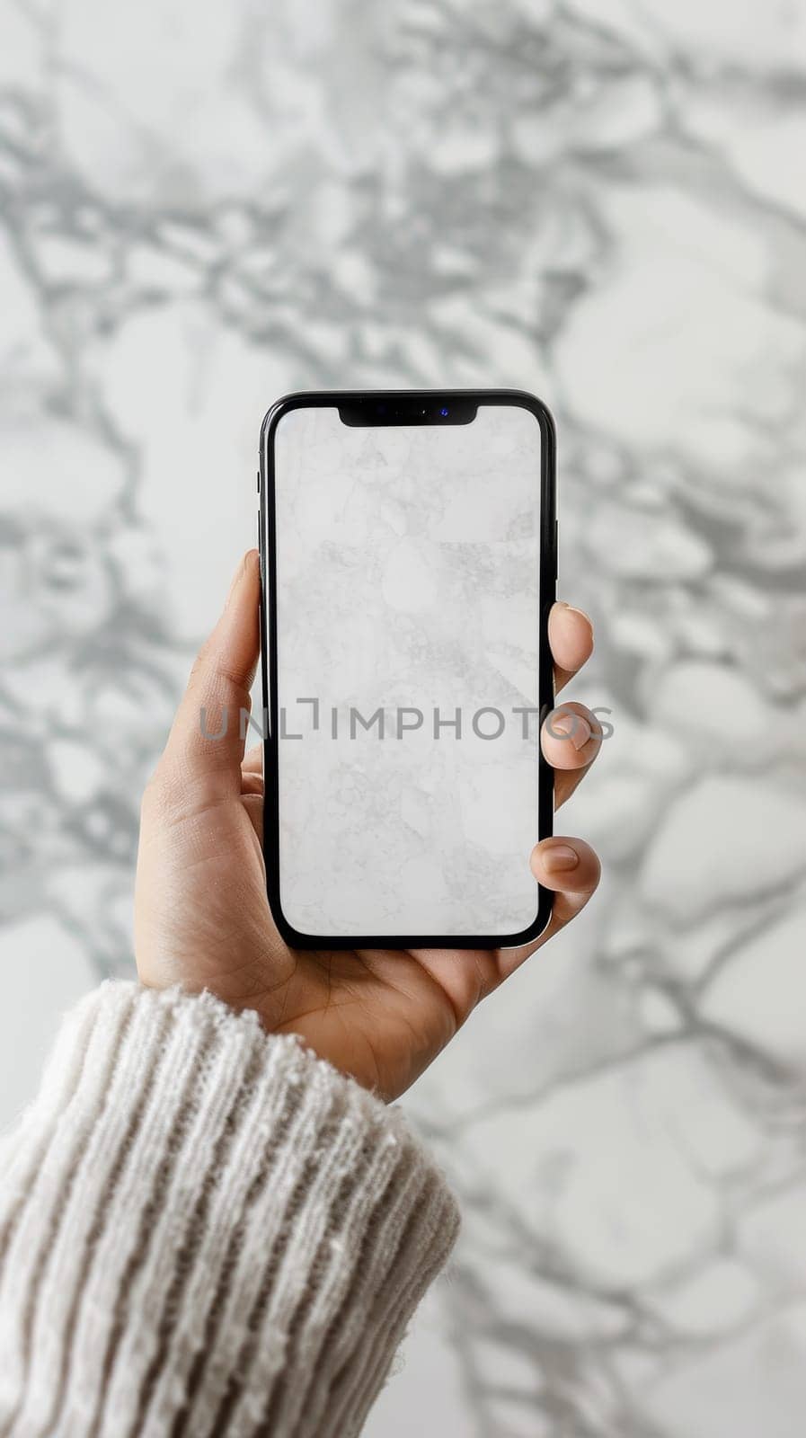A hand holds a modern smartphone with a marble background, showcasing a blank screen for mockups