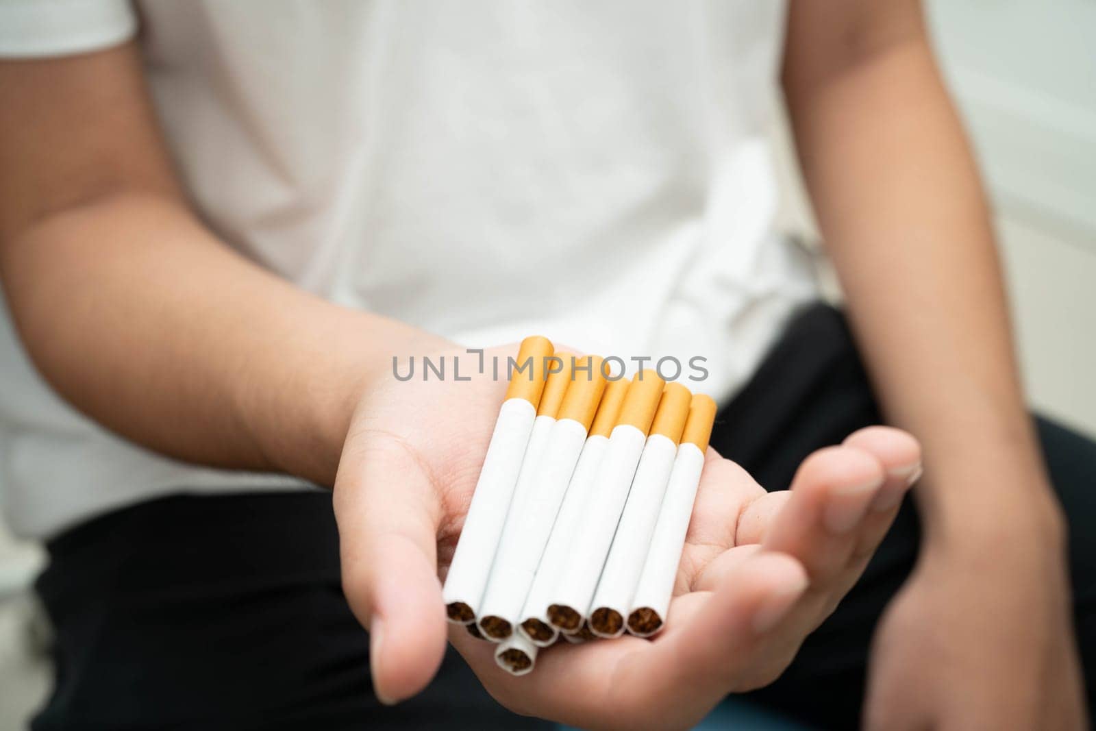 Asian man holding cigarette in hand, no smoking.