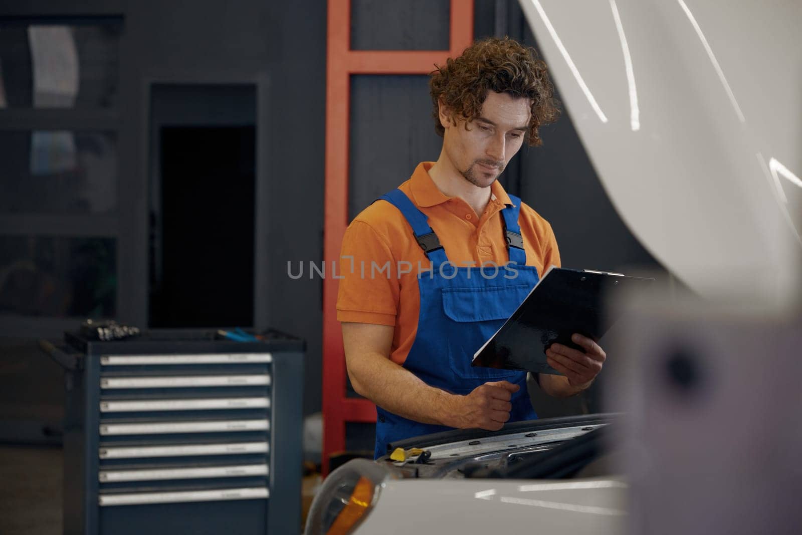 Mechanic looking under car hood checking engine operation work. Auto diagnostic and repair service concept