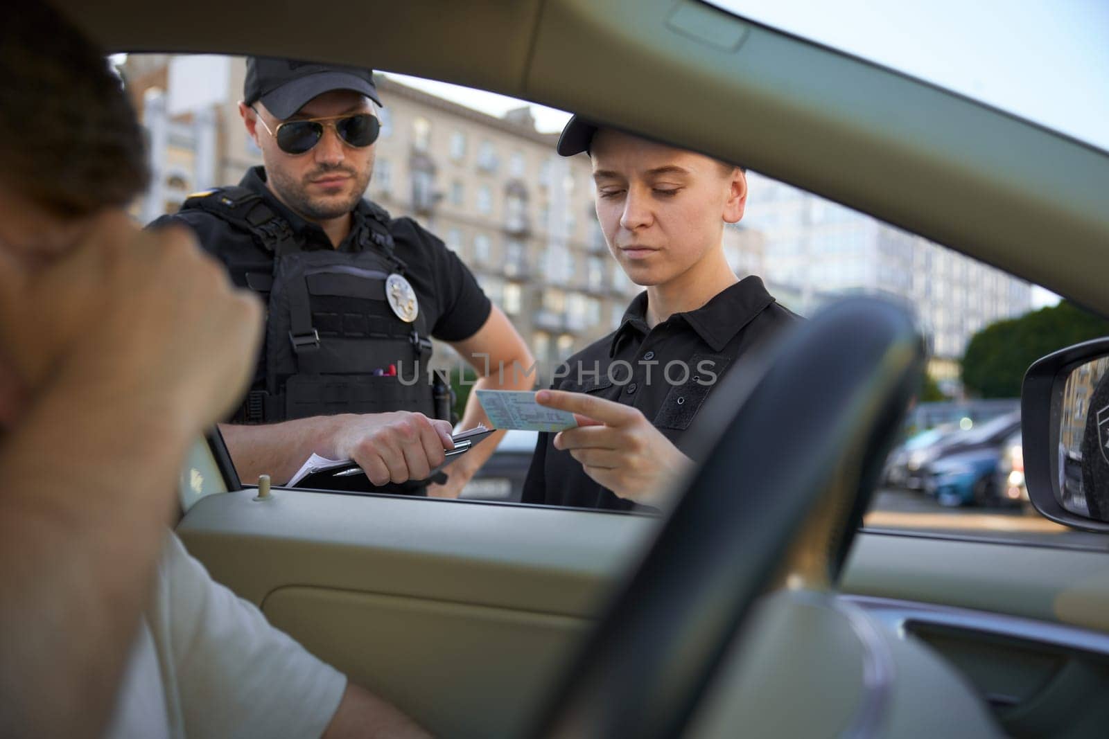 Police officers checking driving license of male driver violated speed traffic rules. Street safety surveillance team at work